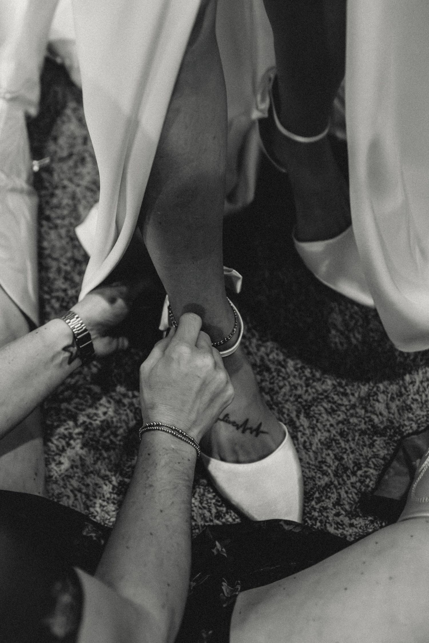 Maid of Honor helps bride put her shoes on during getting ready moments