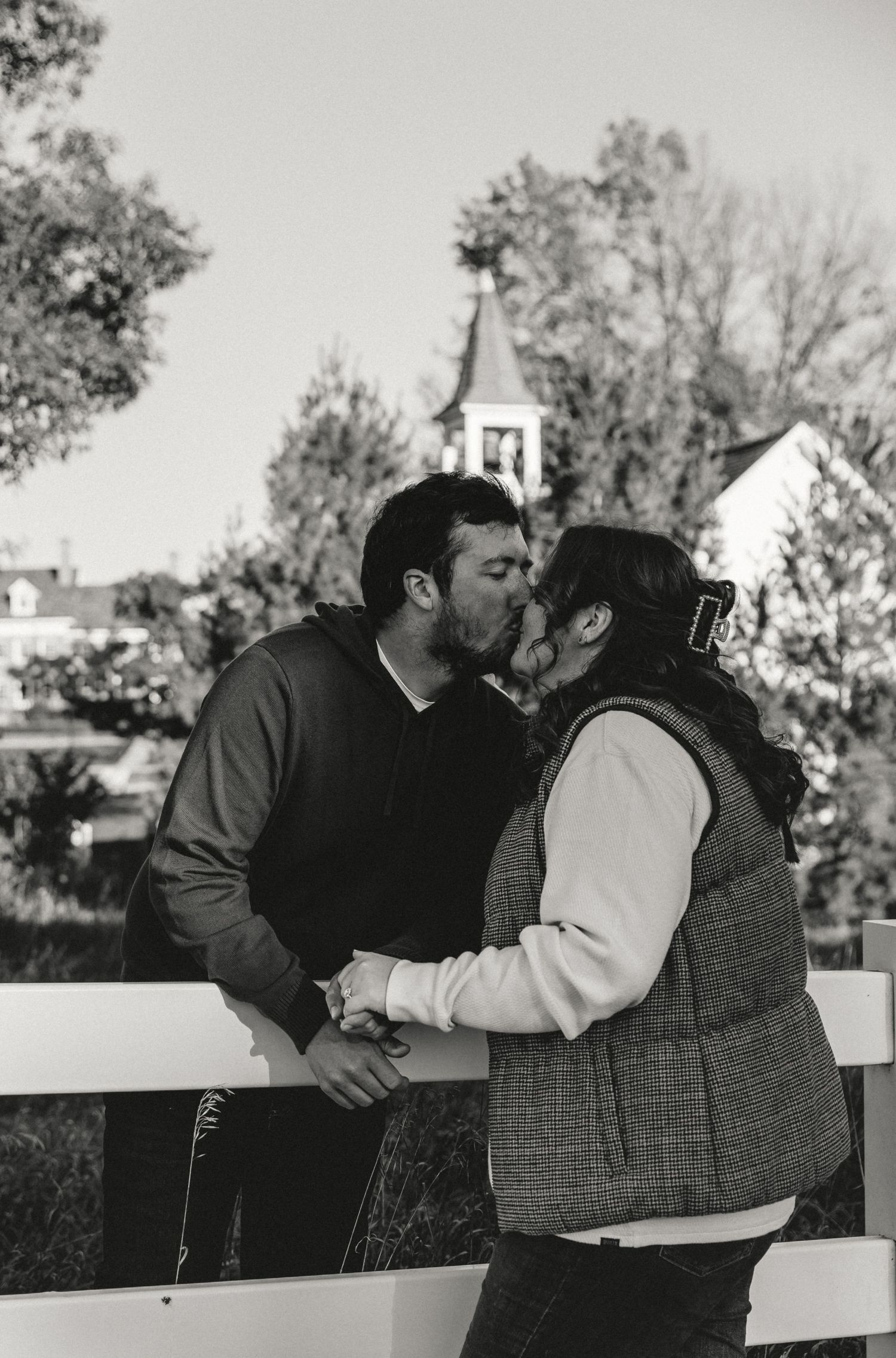 Couple shares a kiss in a farm setting during their golden hour engagement session with illinois wedding photographer