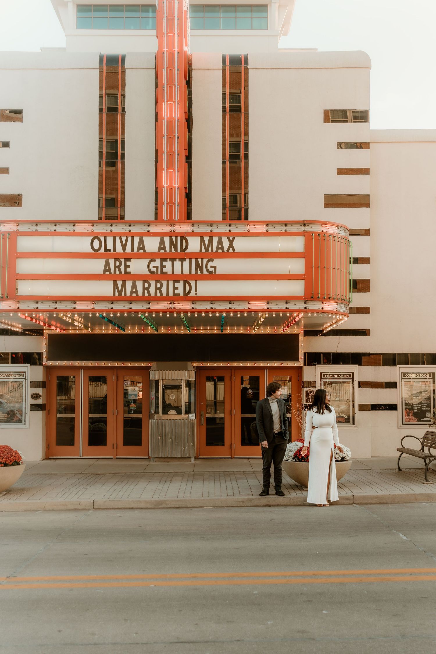 Couple standing in front of a vintage movie theater during their engagement session