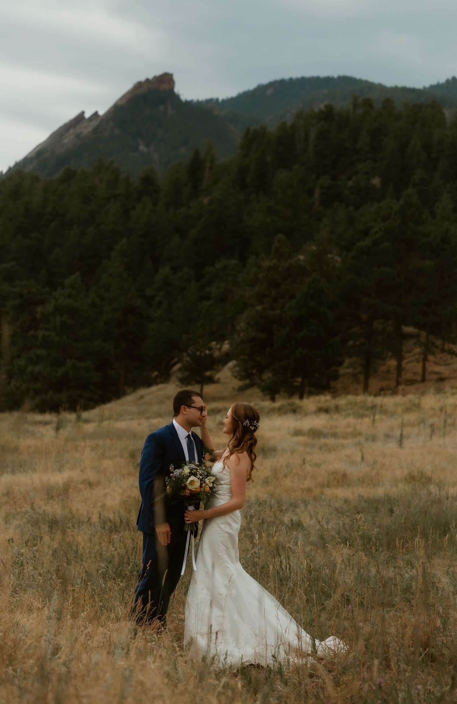 Bride & Groom share an intimate moment in an open field surrounded by mountains during wedding portraits with colorado wedding photographer