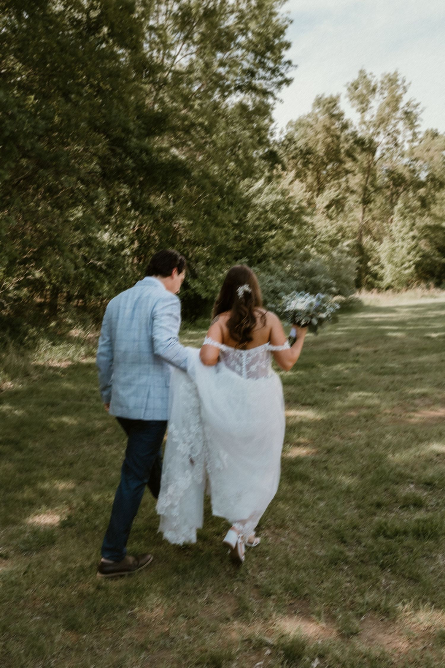 Groom holding brides gown as they take a moment to be with eachother during wedding portraits