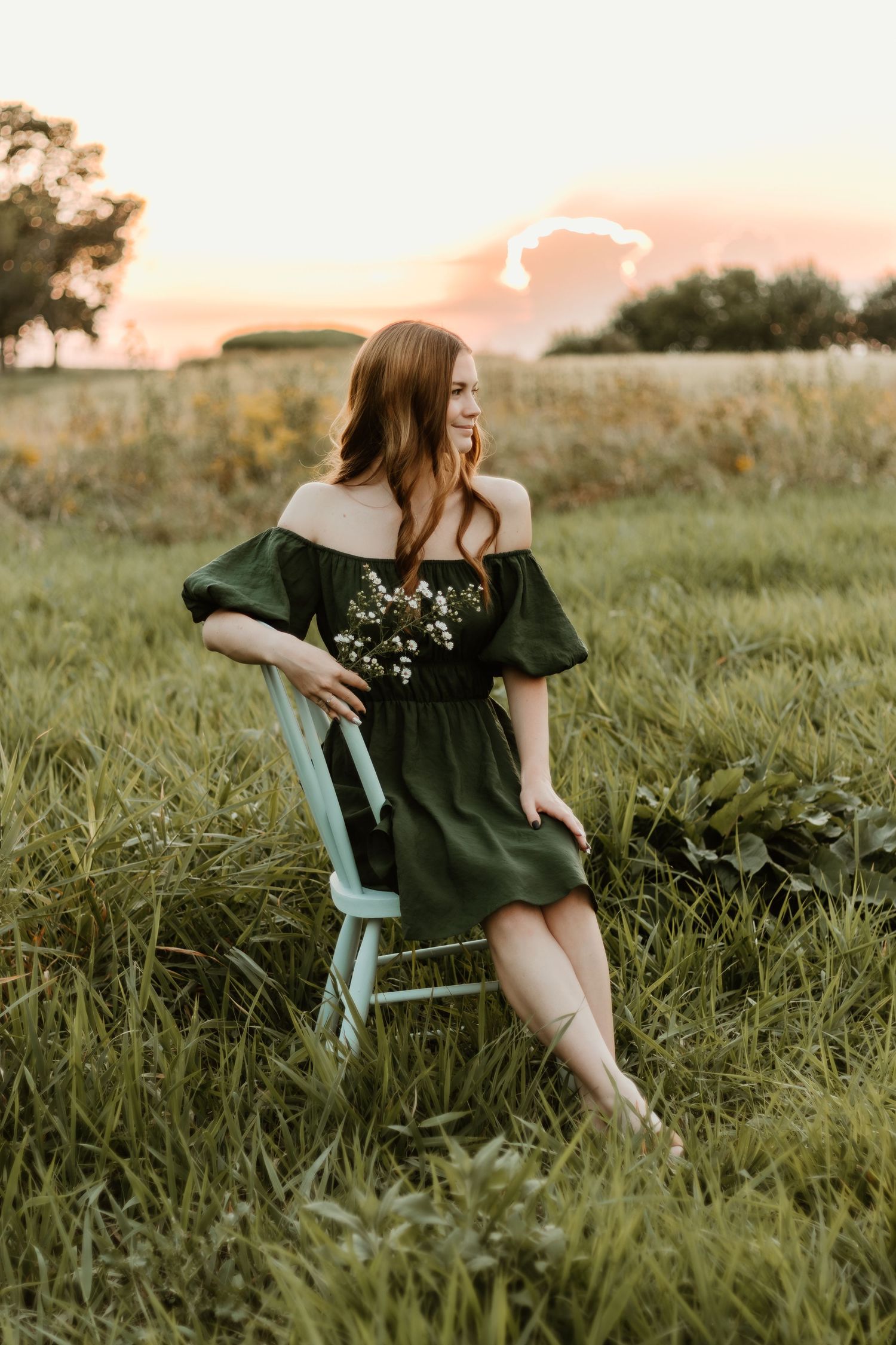 High school senior sits in field for senior photos with central illinois senior photographer