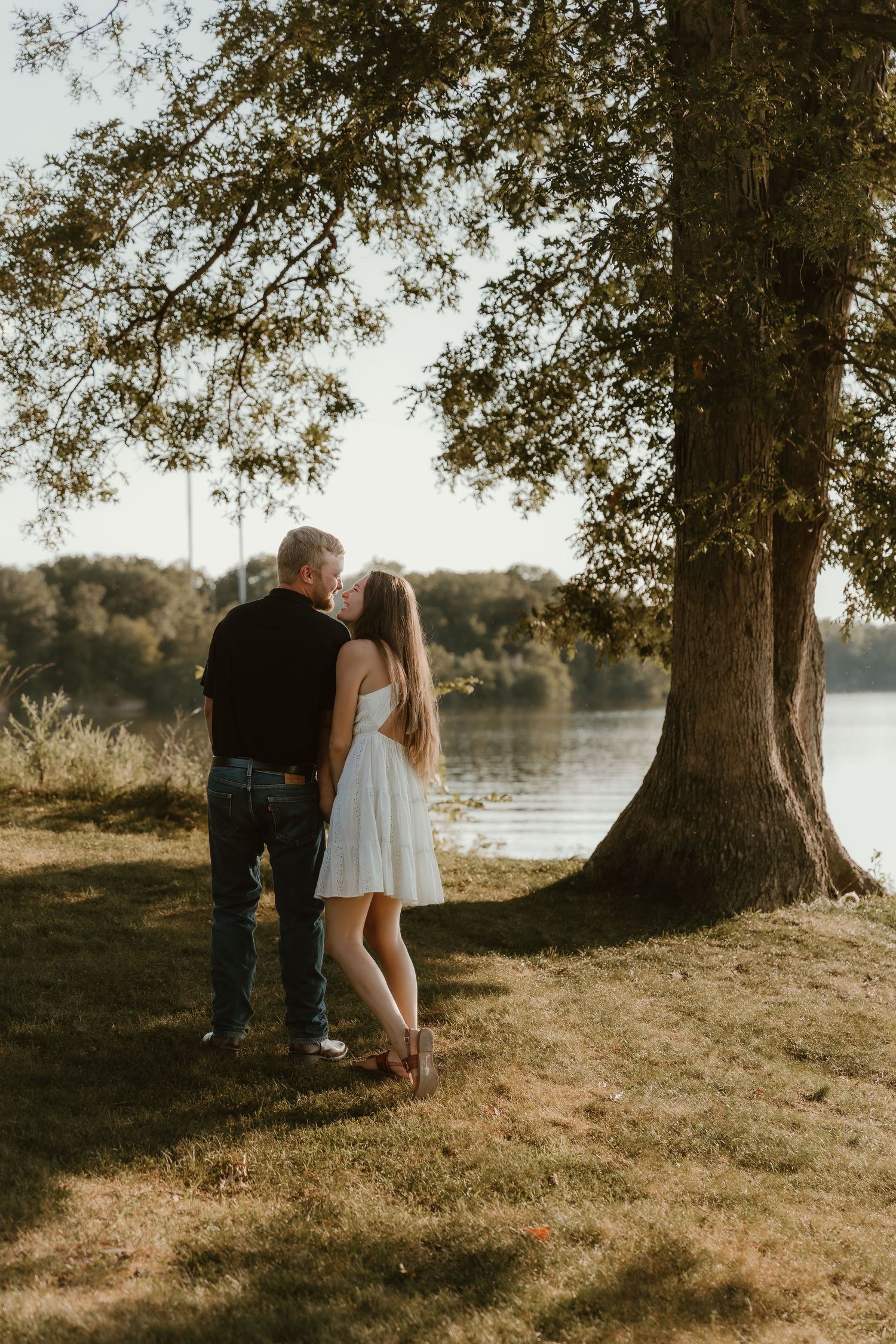 Couple cuddles into each other bathed by the golden light and lake views during their engagement session