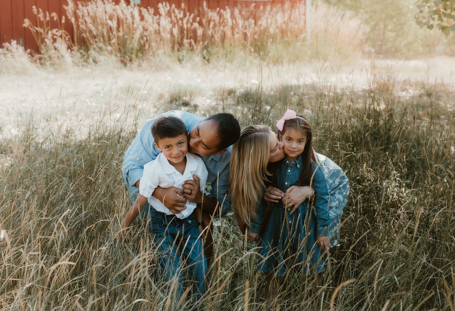 Family cradles each other in a green field during their family session in Greeley, Colorado with family photographer