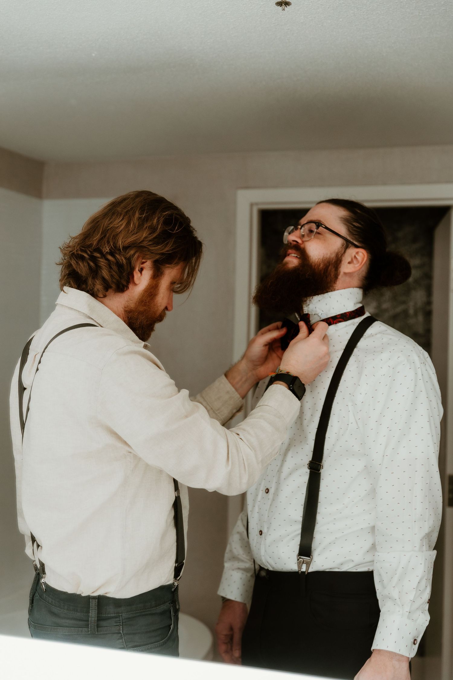 Groomsman helps Groom with his bowtie during a las vegas elopement captured by wedding destination photographer