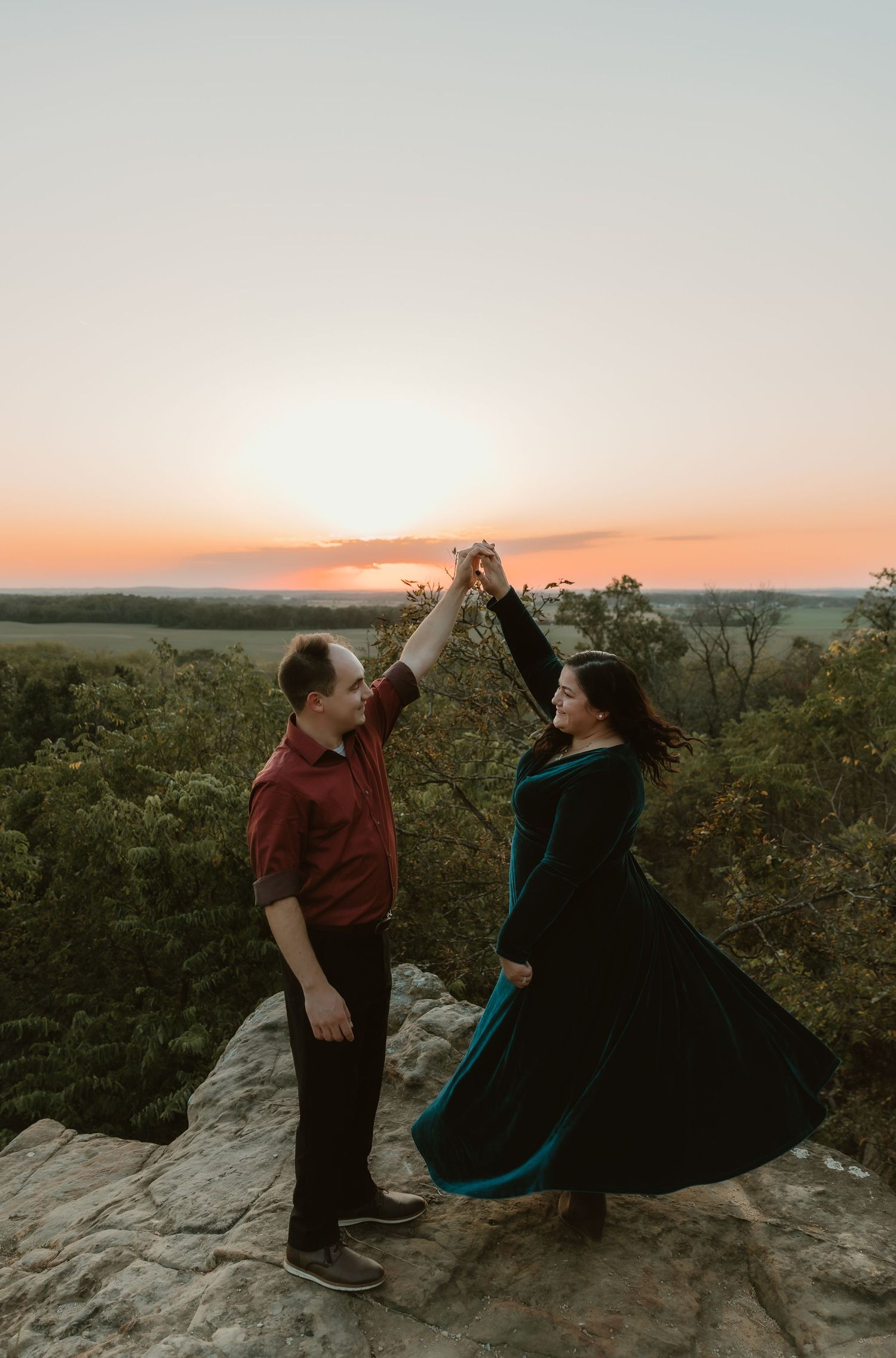 Romantic sunset engagement photo in nature of a couple, where the groom is spinning the bride, being playful and cute