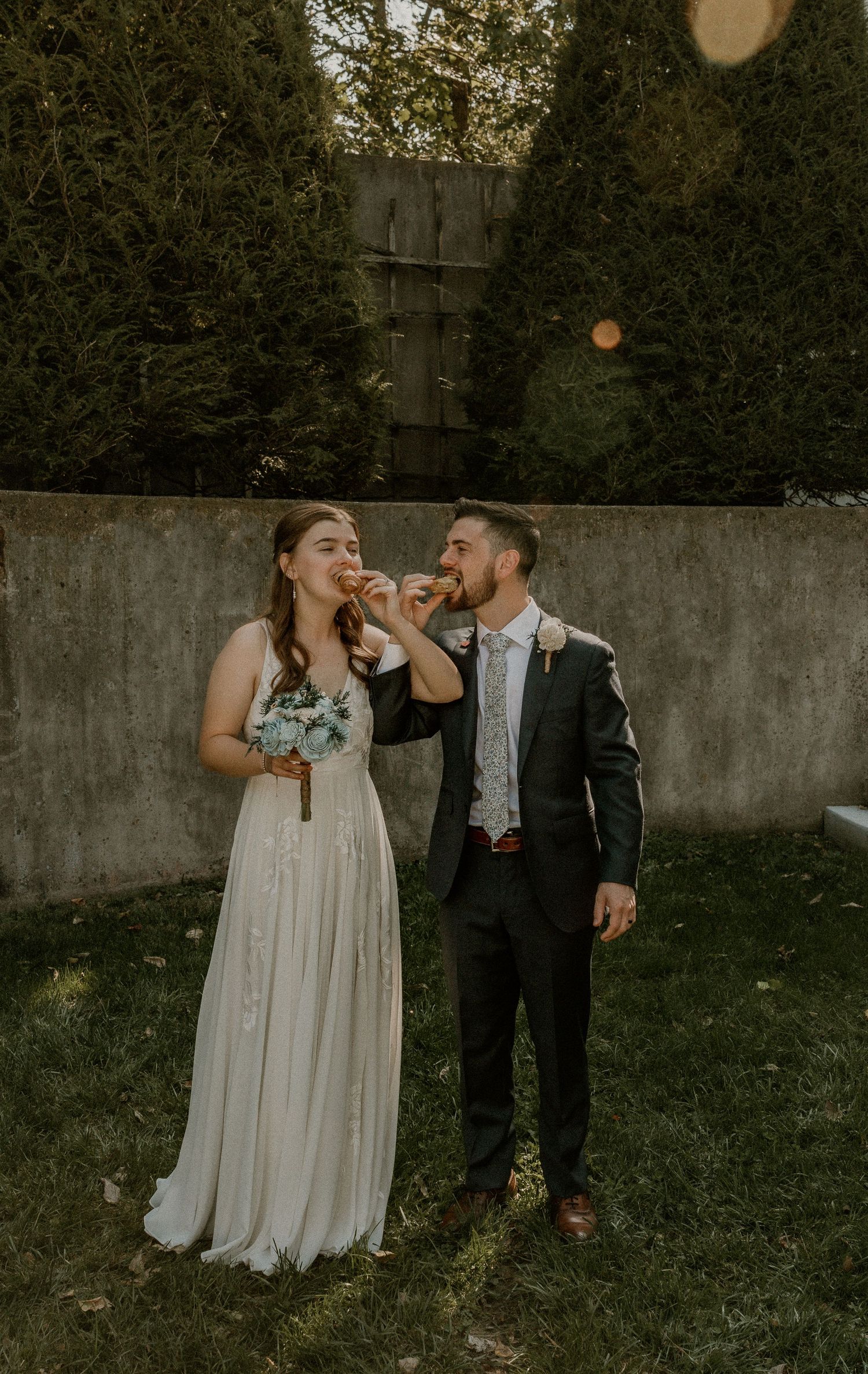 Bride and groom sharing croissants during their portraits, capturing a delightful and intimate wedding moment
