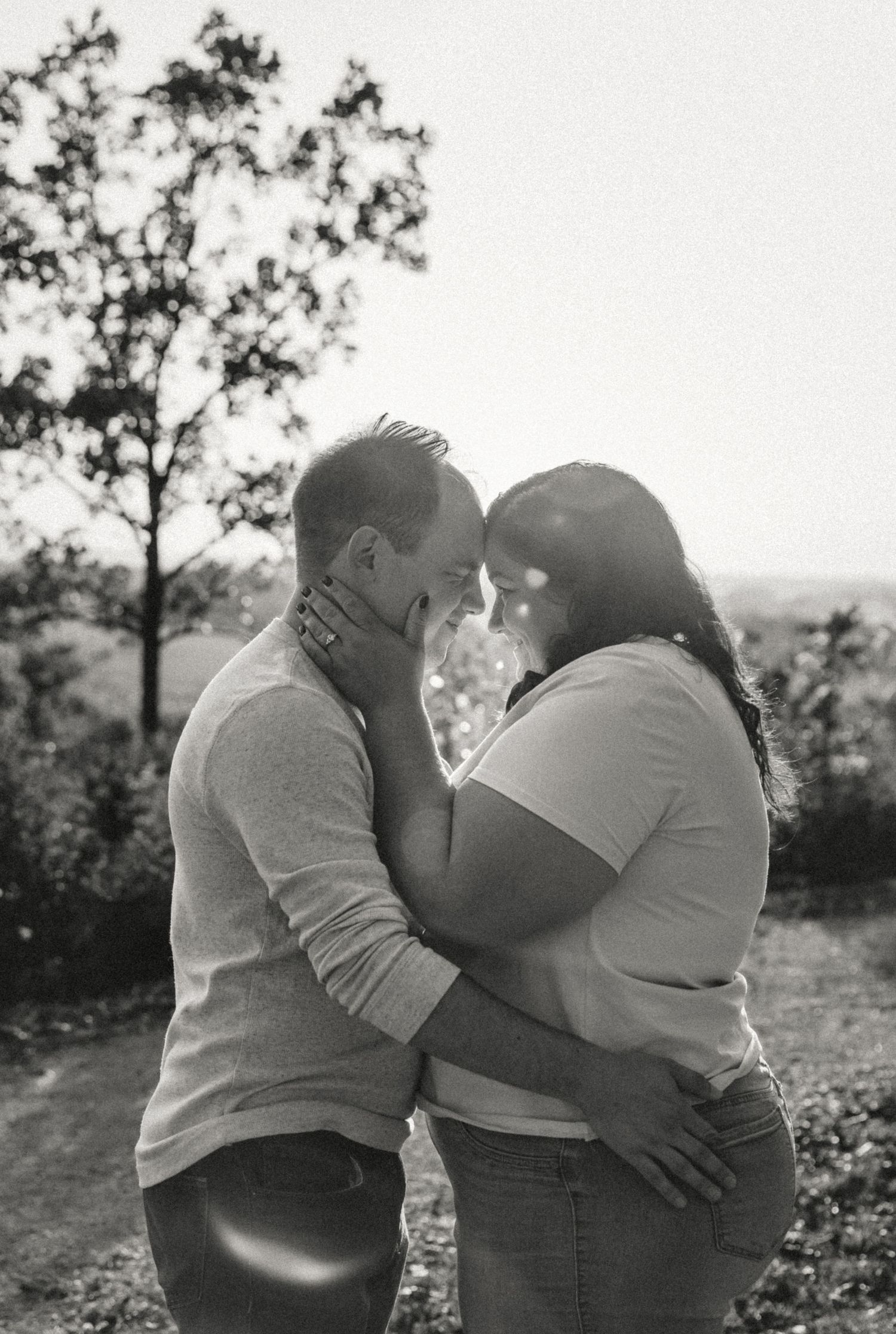 Romantic engagement photo of a couple, gently touching foreheads bathed in golden light. highlighting emotional connection