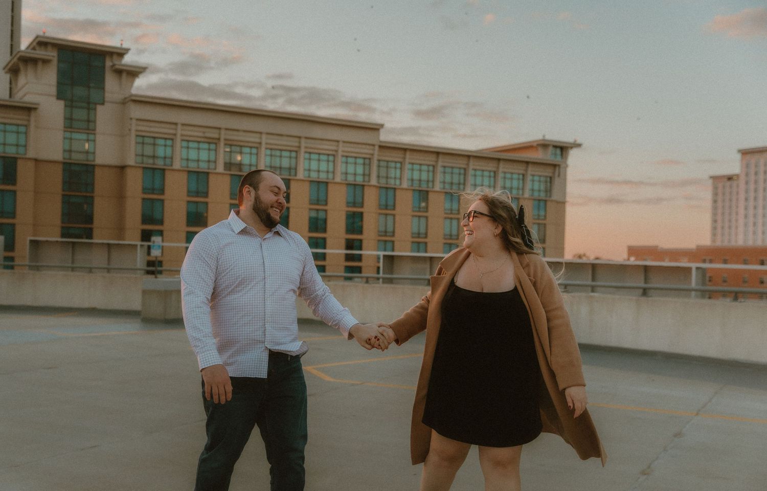 Couple strolls on a garage rooftop during their engagement session with central illinois wedding photographer