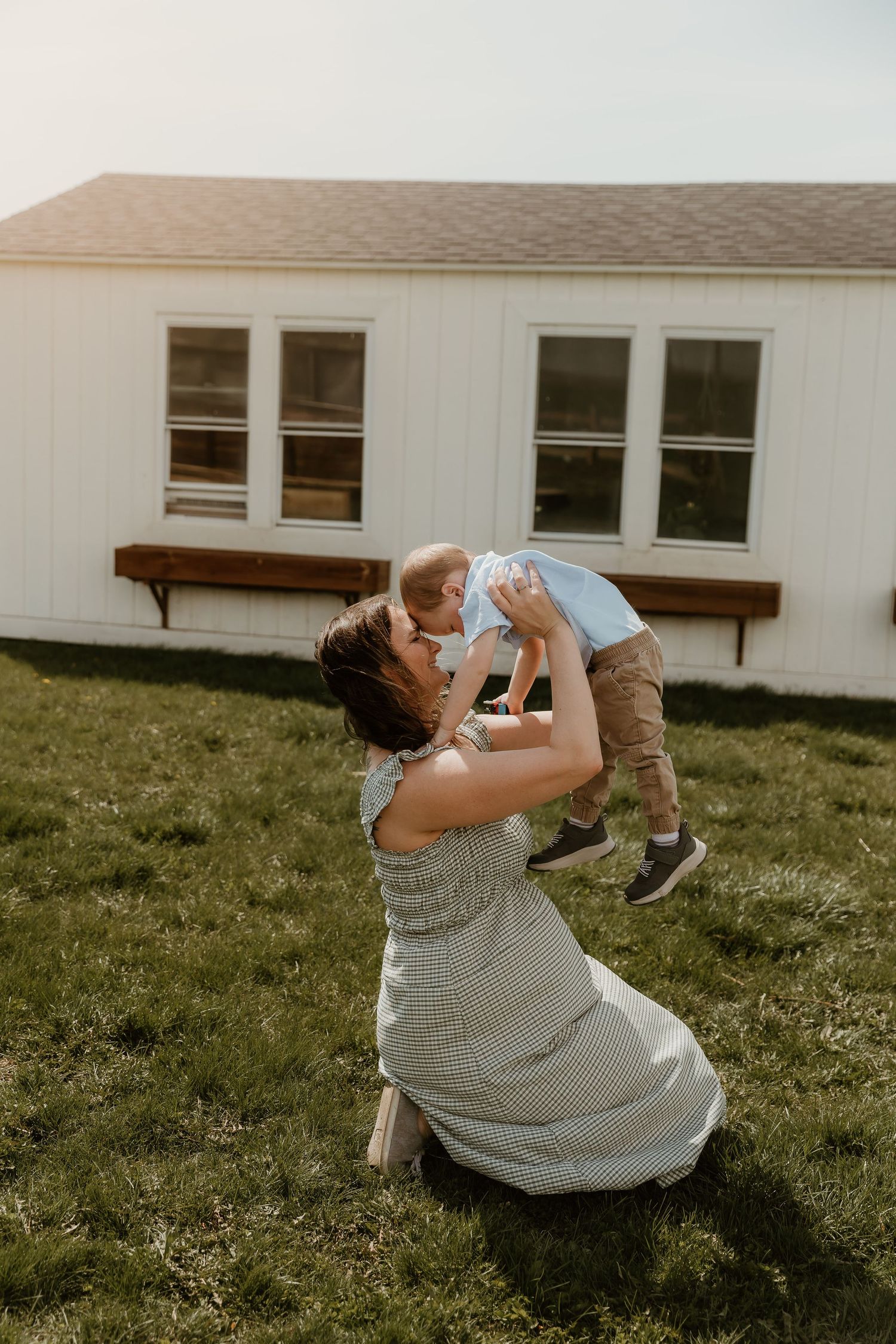 mother lifts son in the air during a playful moment with bloomington normal il photographer
