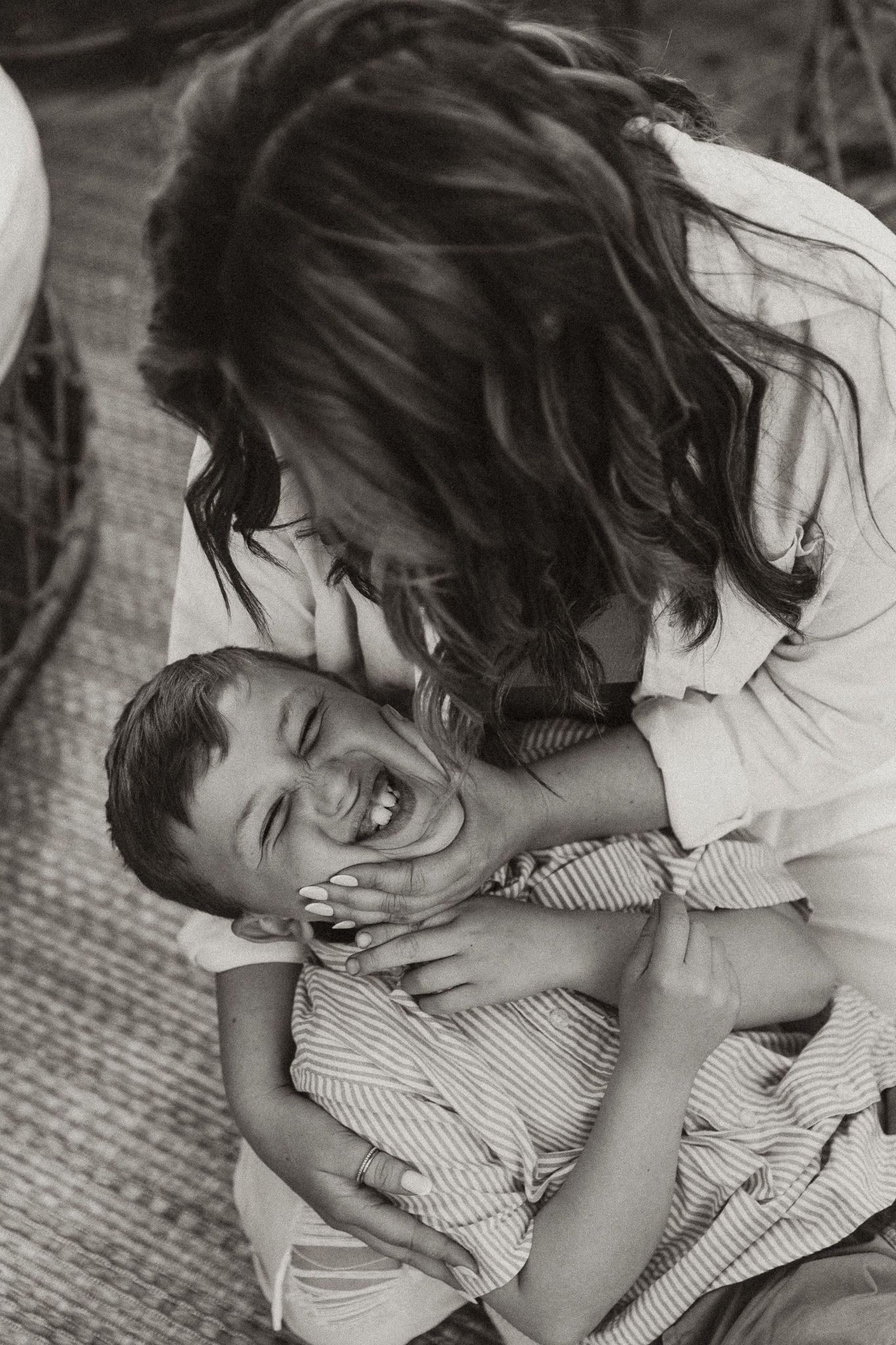 Mother squeezes her son's face during a playful family session with central illinois family photographer