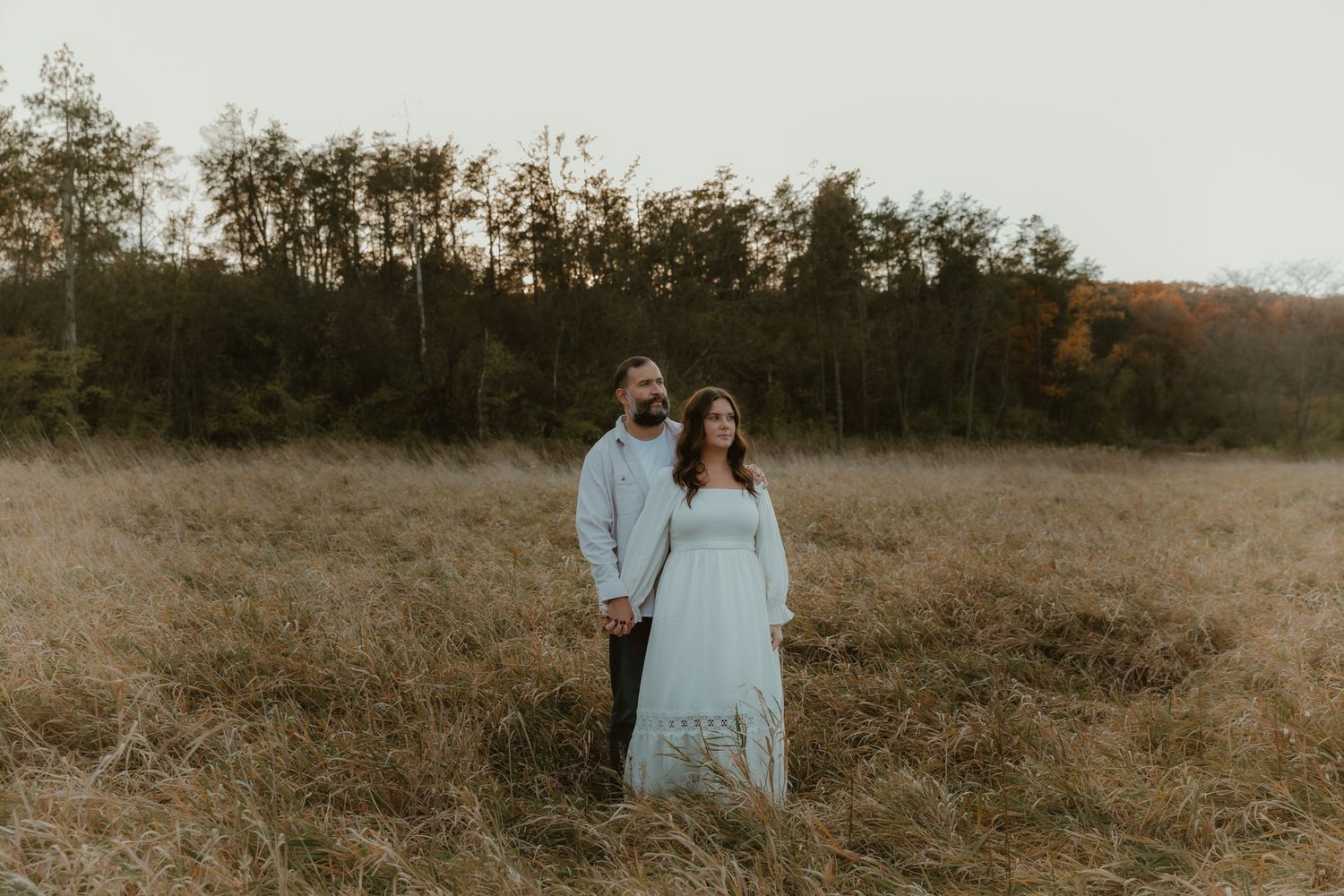 Couple cuddles into each other in an open field during their engagement photography session with illinois engagement photographer