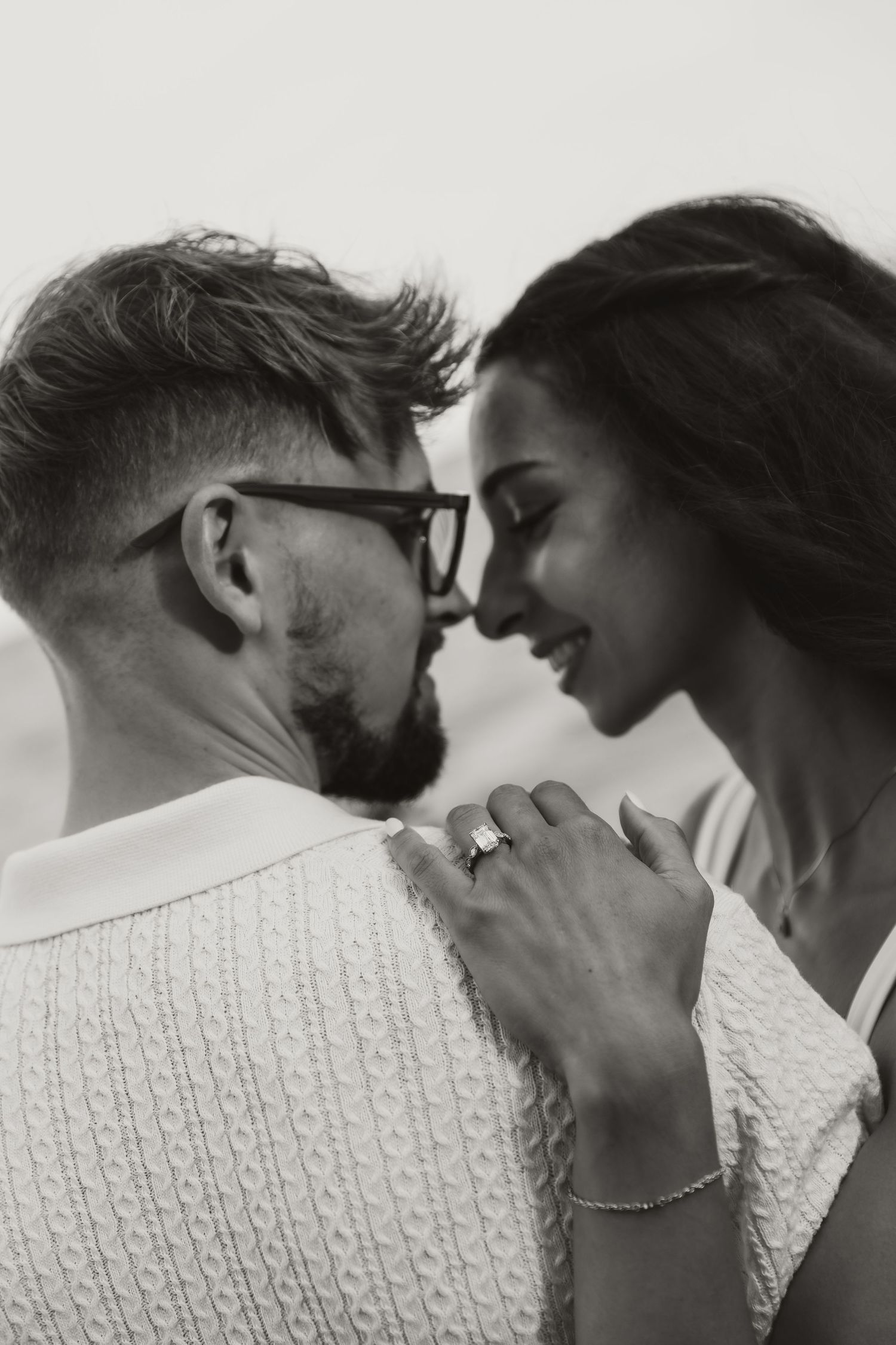 Black-and-white close-up of engaged couple sharing an intimate moment. Emotional, timeless portrait highlighting love and connection.