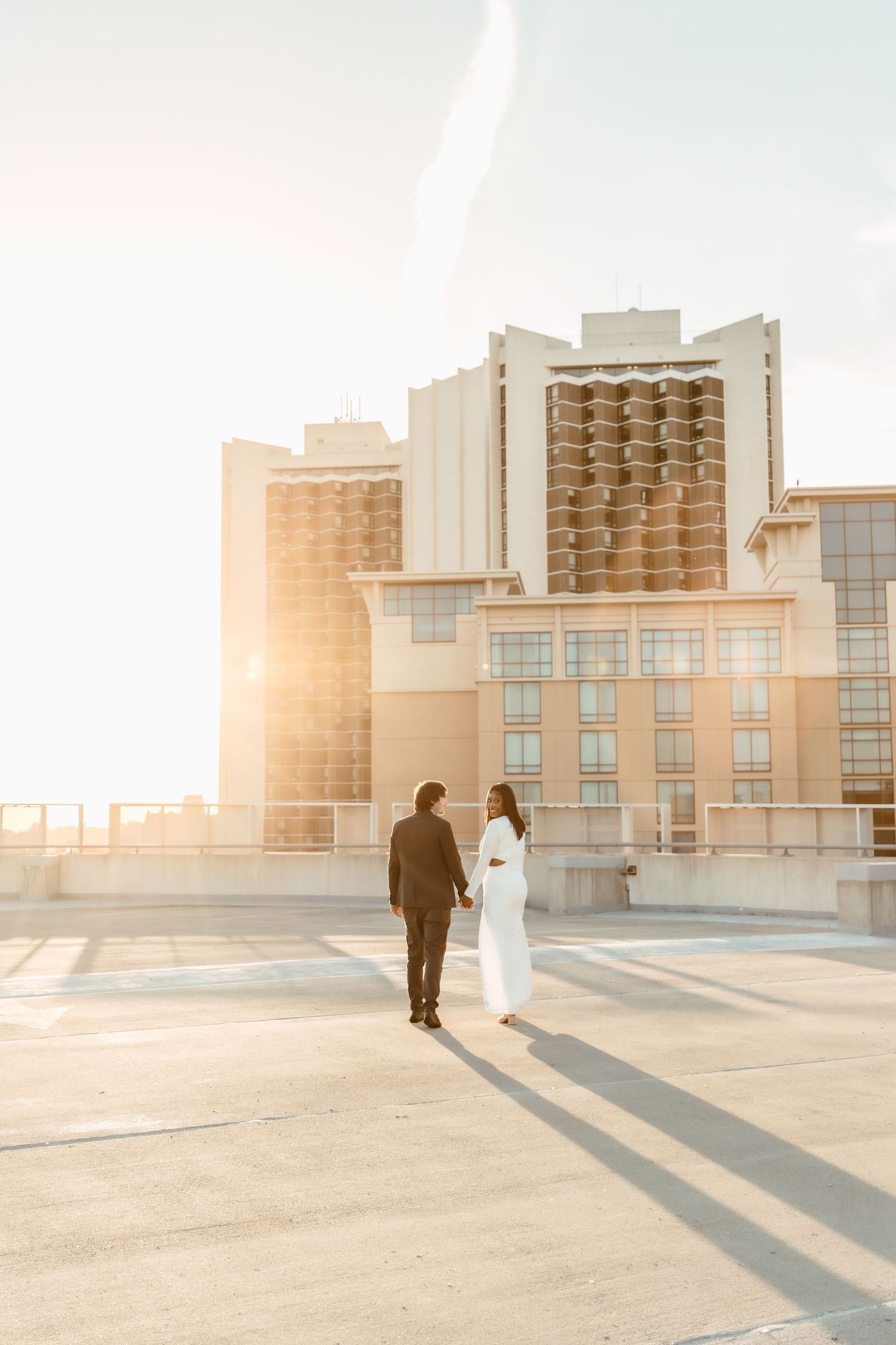 Couple walking away into the sunset on a parking garage roof during their engagement photoshoot with central il couples photographer