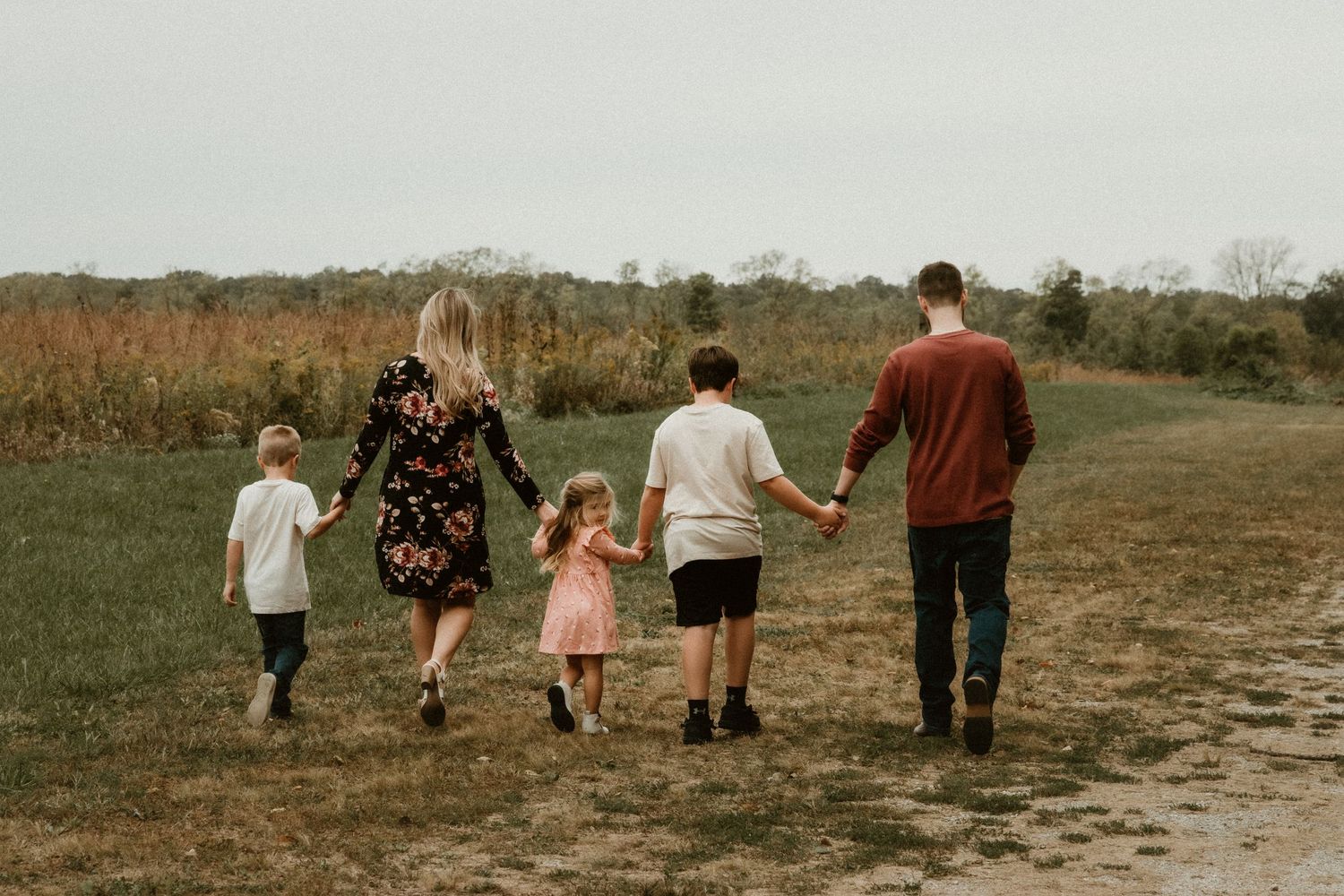 Family holds hands while taking a stroll through funks grove nature area for a family photo session with central il family photographer