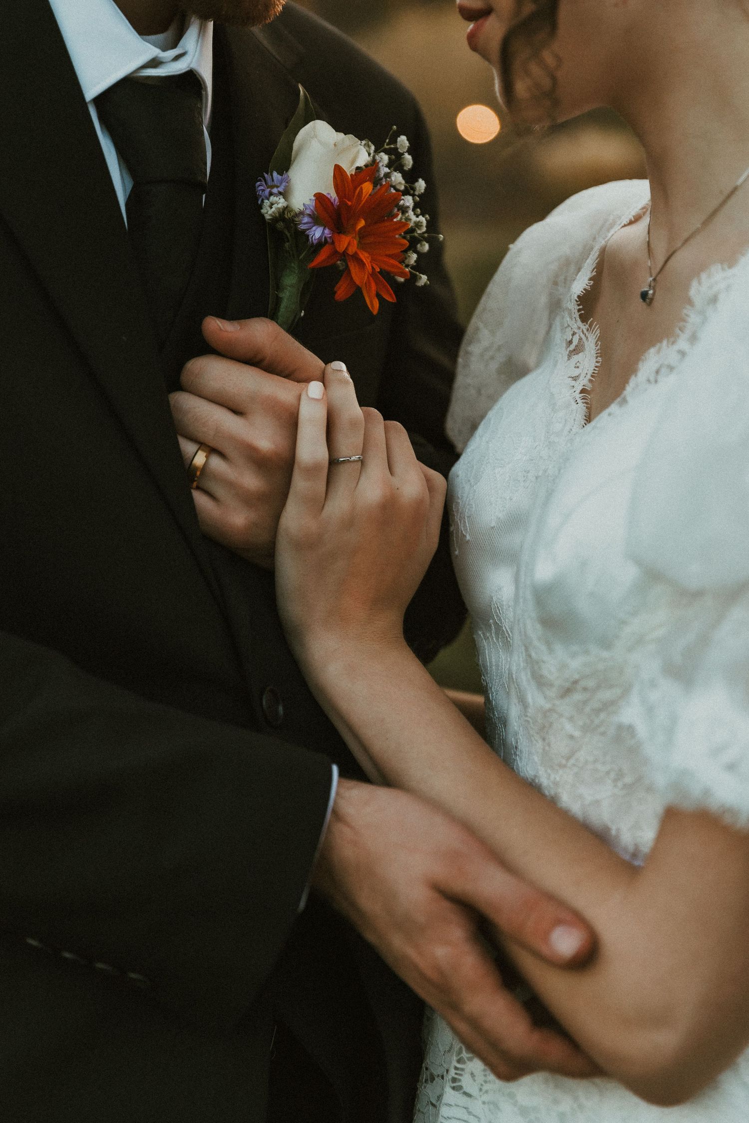 Close-up of bride and groom holding hands, showcasing their wedding rings and commitment to each other ; Michigan Elopement Photographer