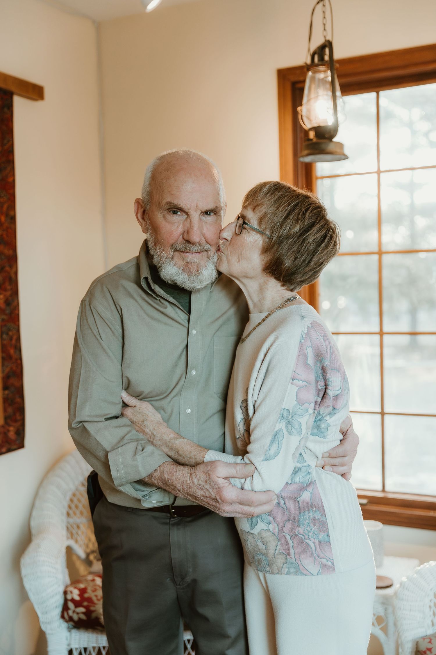 wife kisses husbands cheek during a photo session for their 50th anniversary