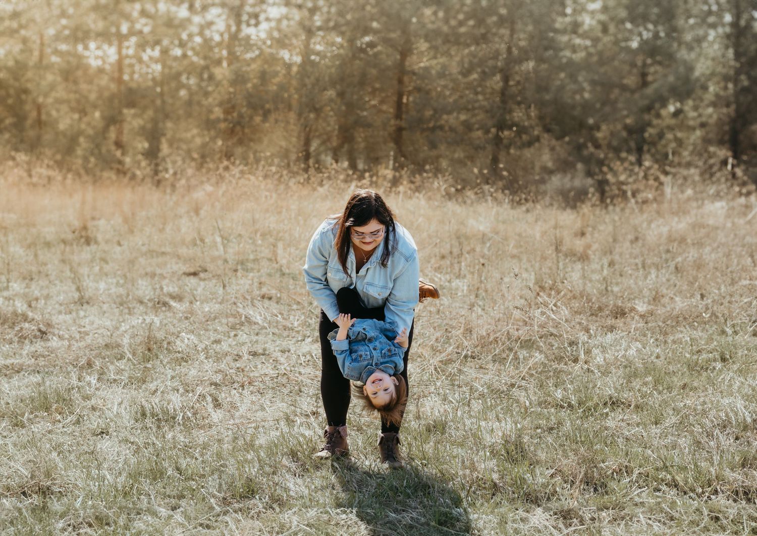 Mom playfully swinging her child toward the ground, making the child laugh during a mom-and-me photo session