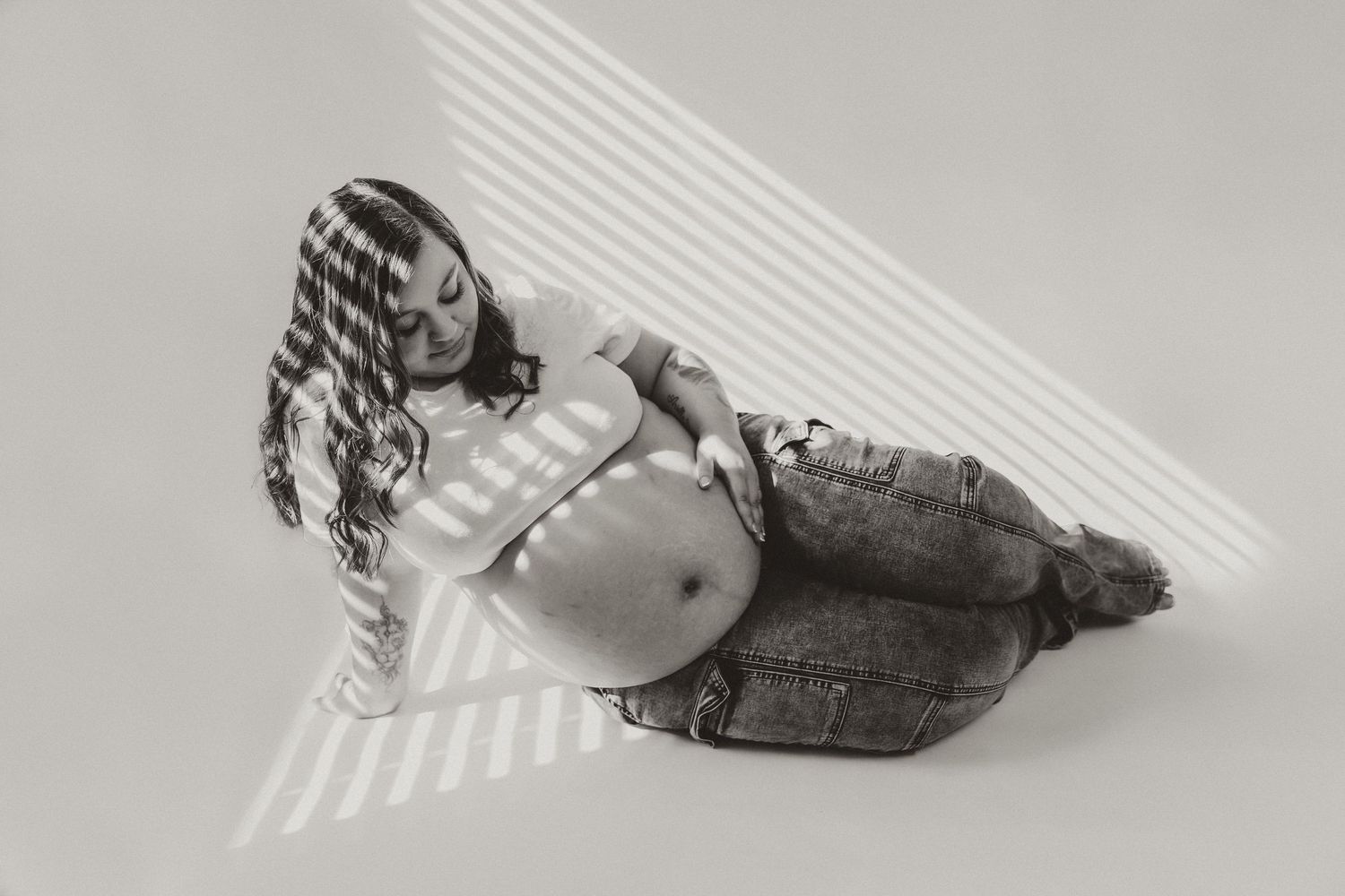 Expecting mother lays out and holds her belly for a photo during a maternity session with central illinois maternity photographer