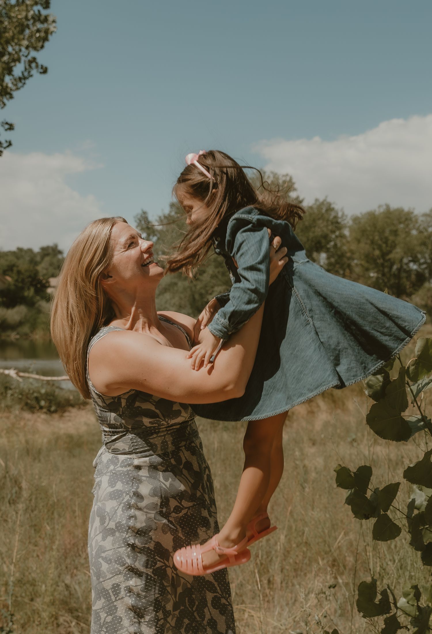 Mother swings her daughter in the air during a playful family session in Greeley, CO with family photographer