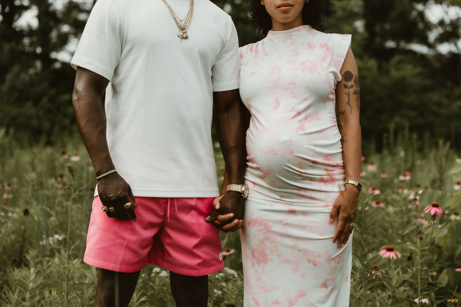 Expecting parents hold each other's hand while taking a detail photo of her baby belly during a maternity photography session in Normal, IL