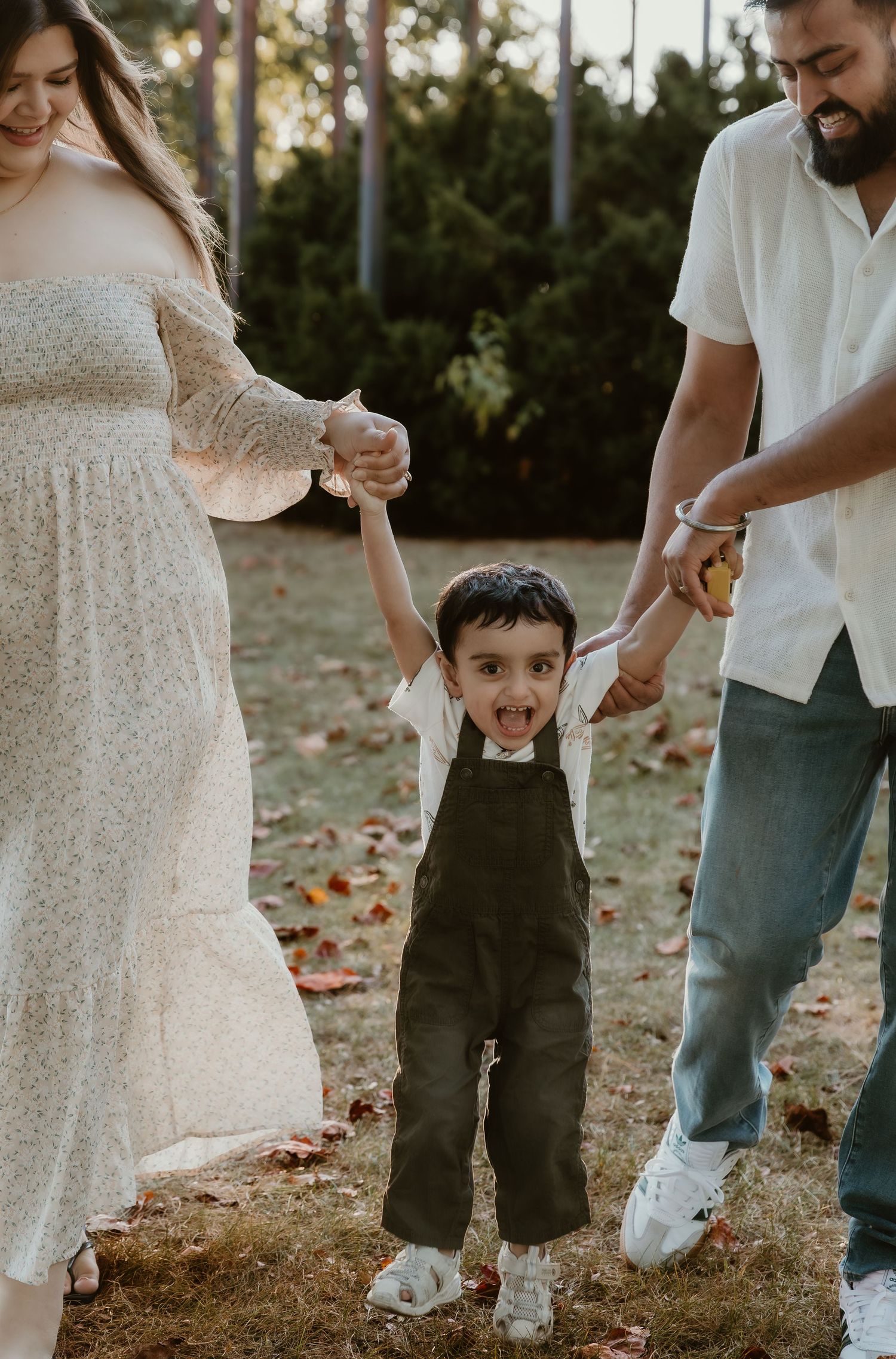 Mom and dad holding their son's hand during a family session in Bloomington, IL