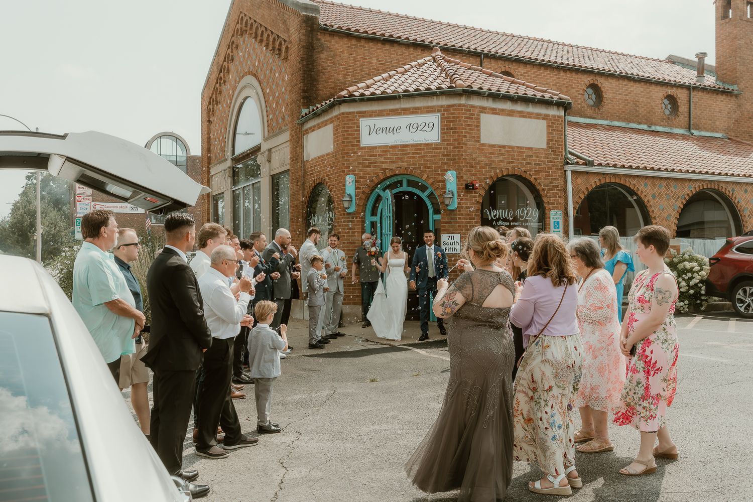 Bride and Groom exit their venue during a bubble and limo ride exit for wedding portraits with illinois wedding photographer