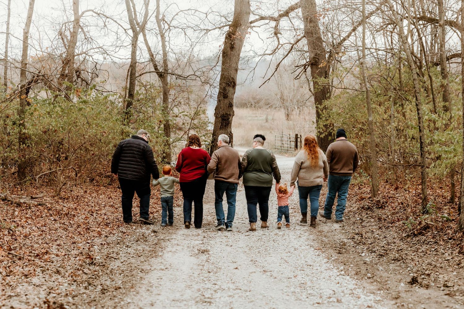 Extended family holds hands and walks down path reminiscing on their days