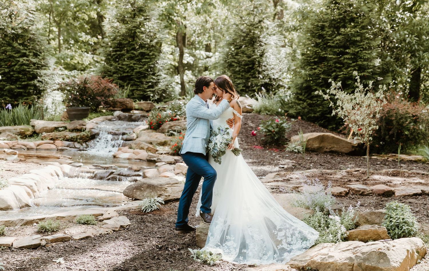 Bride and Groom take an intimate moment to themselves in front of a waterfall at dragonfly wedding venue captured by central il photographer