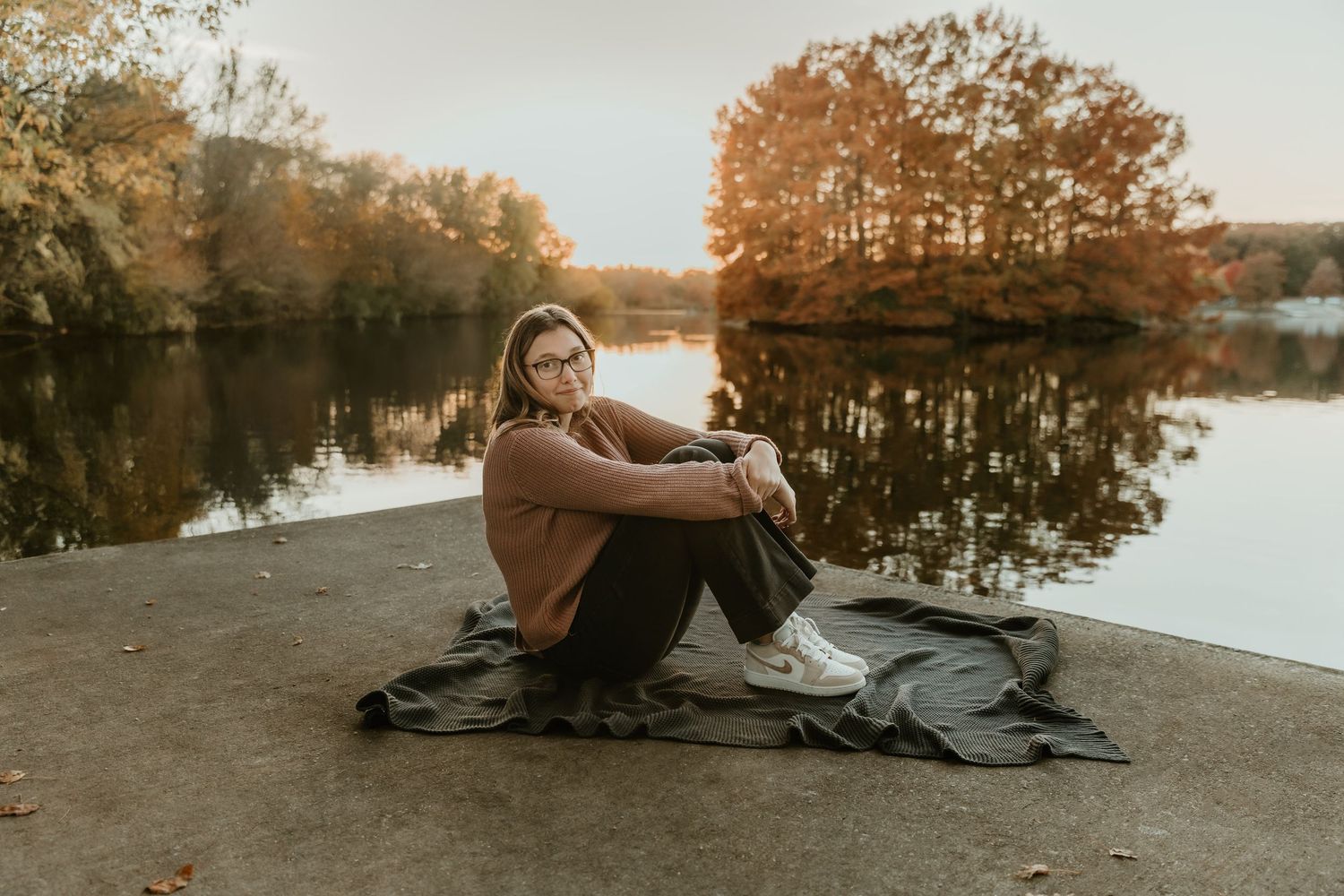 High school senior poses in front of Moraine View lake for a senior portrait captured by central illinois senior photographer