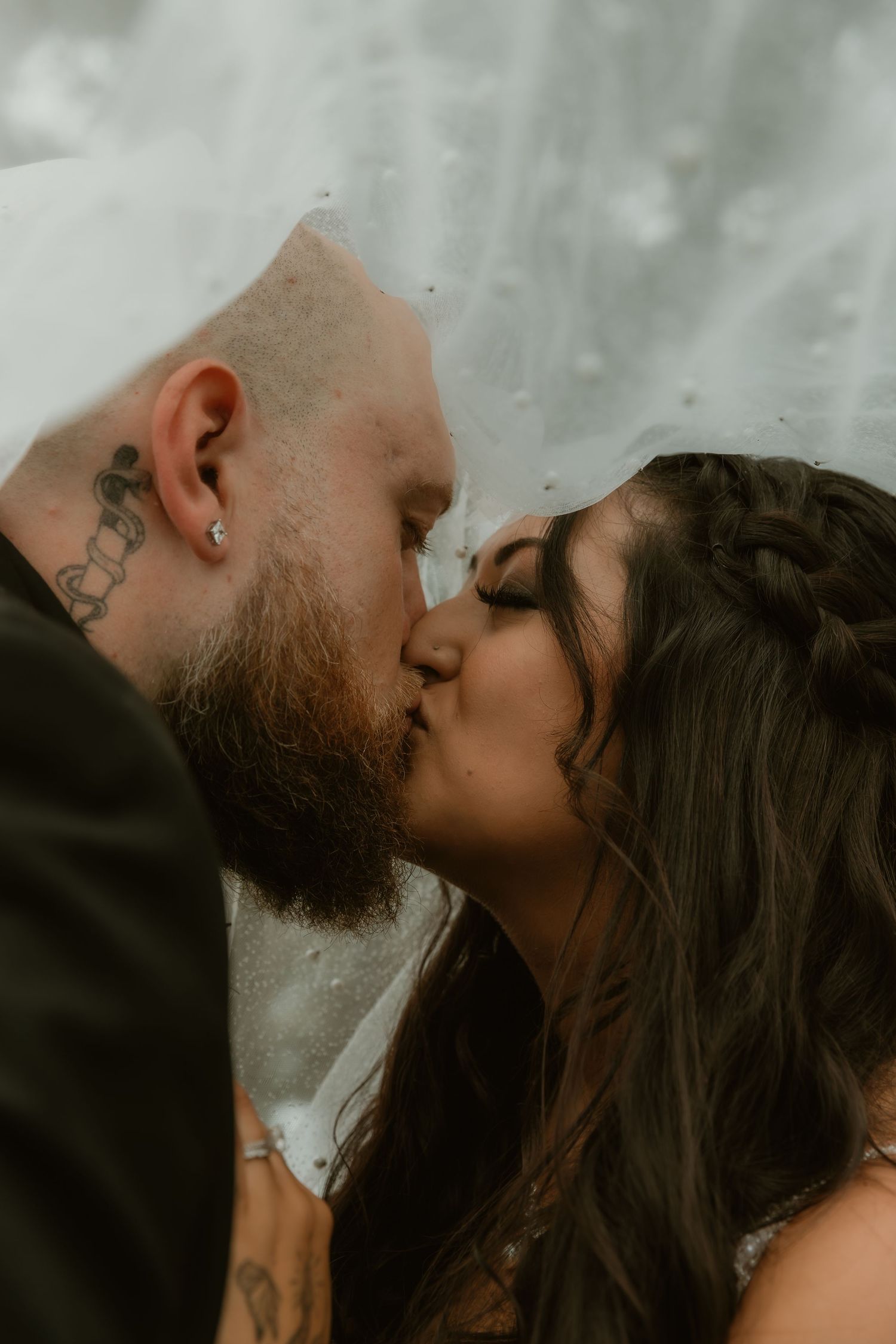 Bride and Groom share a kiss under the veil during wedding portraits in Sycamore, IL captured by illinois wedding photographer