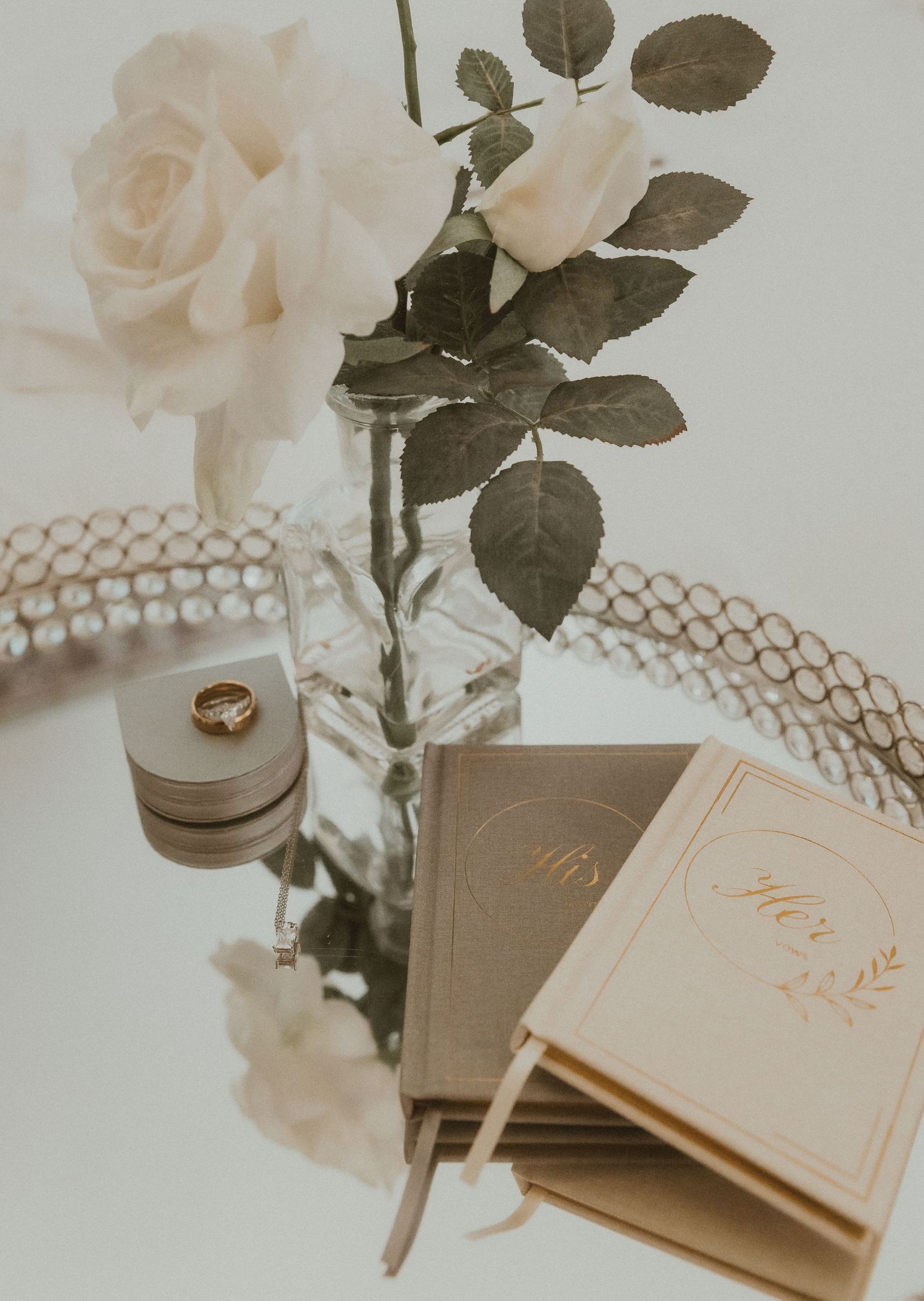 Wedding details of bride and grooms wedding rings, vow books, jewelry, and flowers photographed by illinois wedding photographer