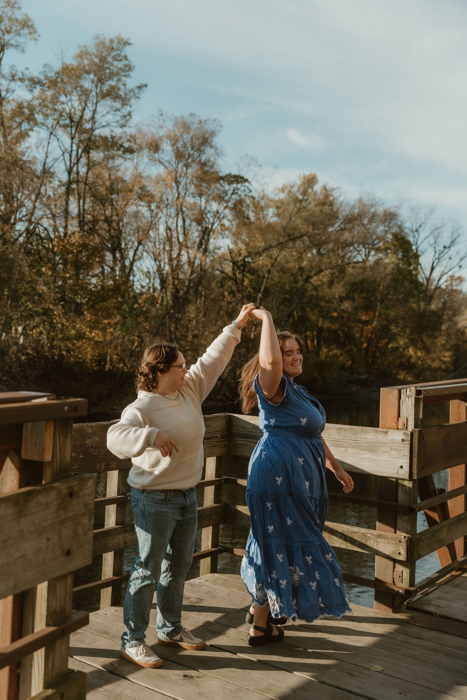Couple dances on a boardwalk during golden hour to capture their engagement with michigan wedding photographer