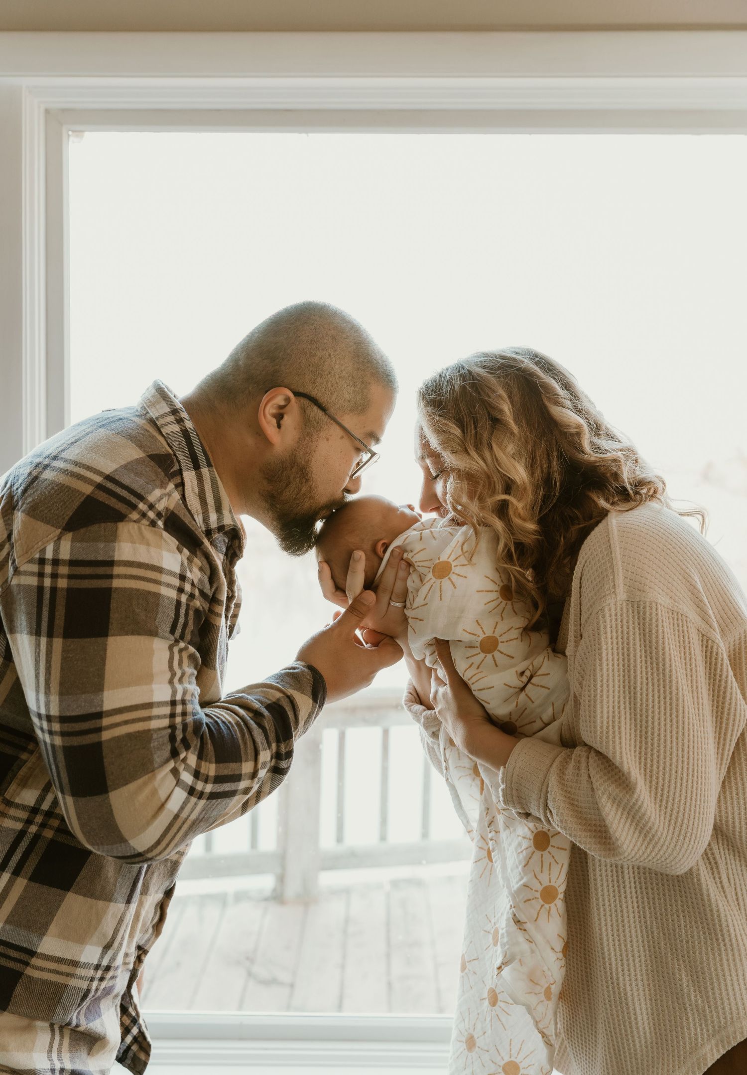 Mom and dad kissing newborn during a lifestyle newborn session with Central Illinois Family Photographer