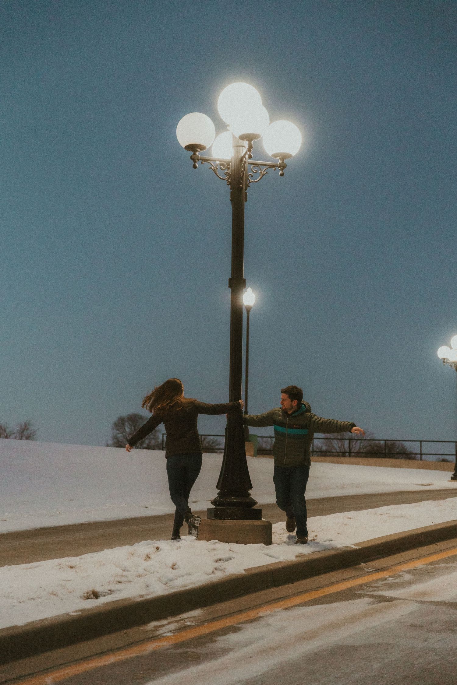 A couple dances around a vintage light pole during a couples photo session