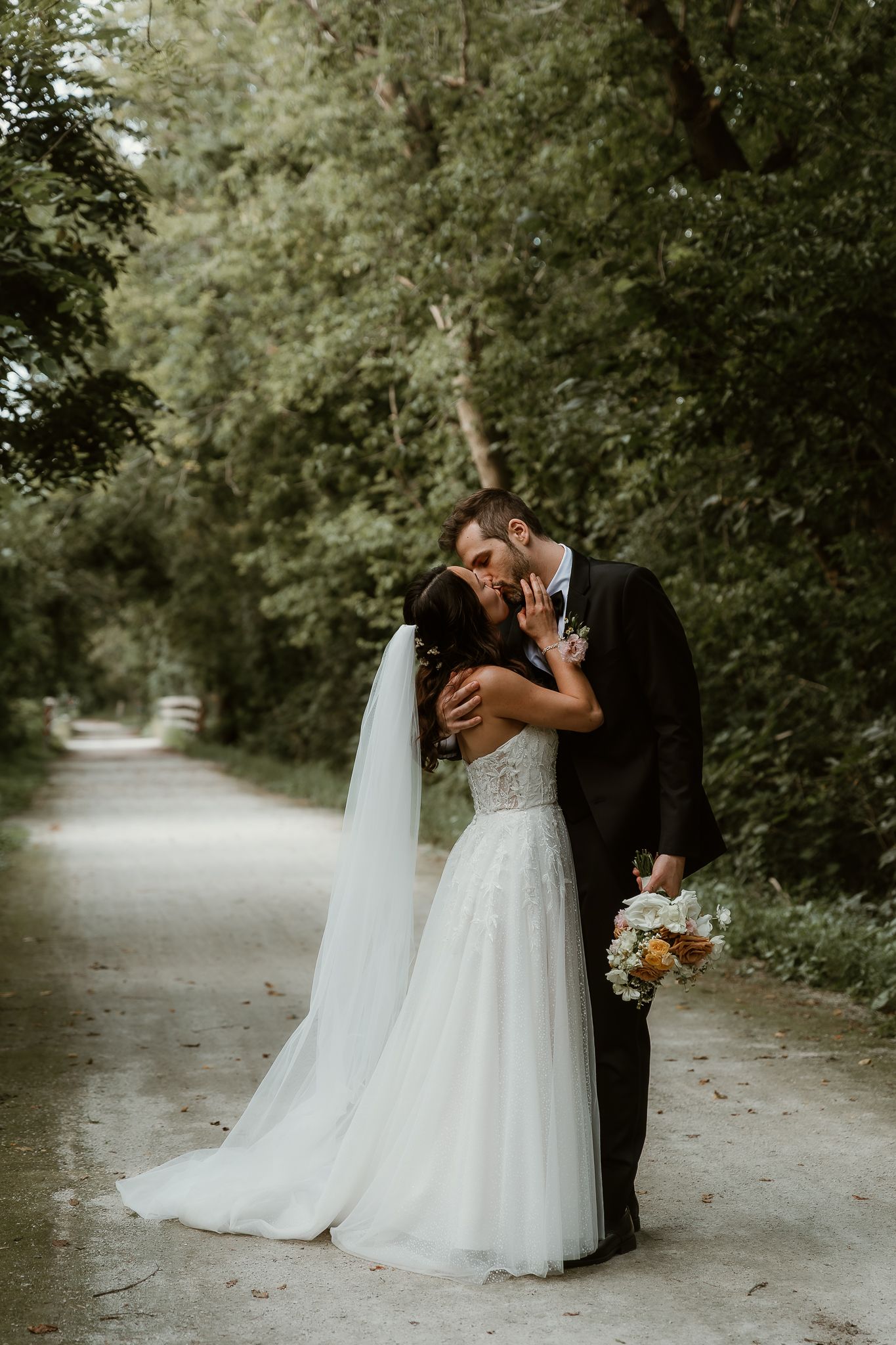 Bride and Groom share an intimate kiss surrounded by fairytale woods during their wedding portraits with illinois wedding photographer