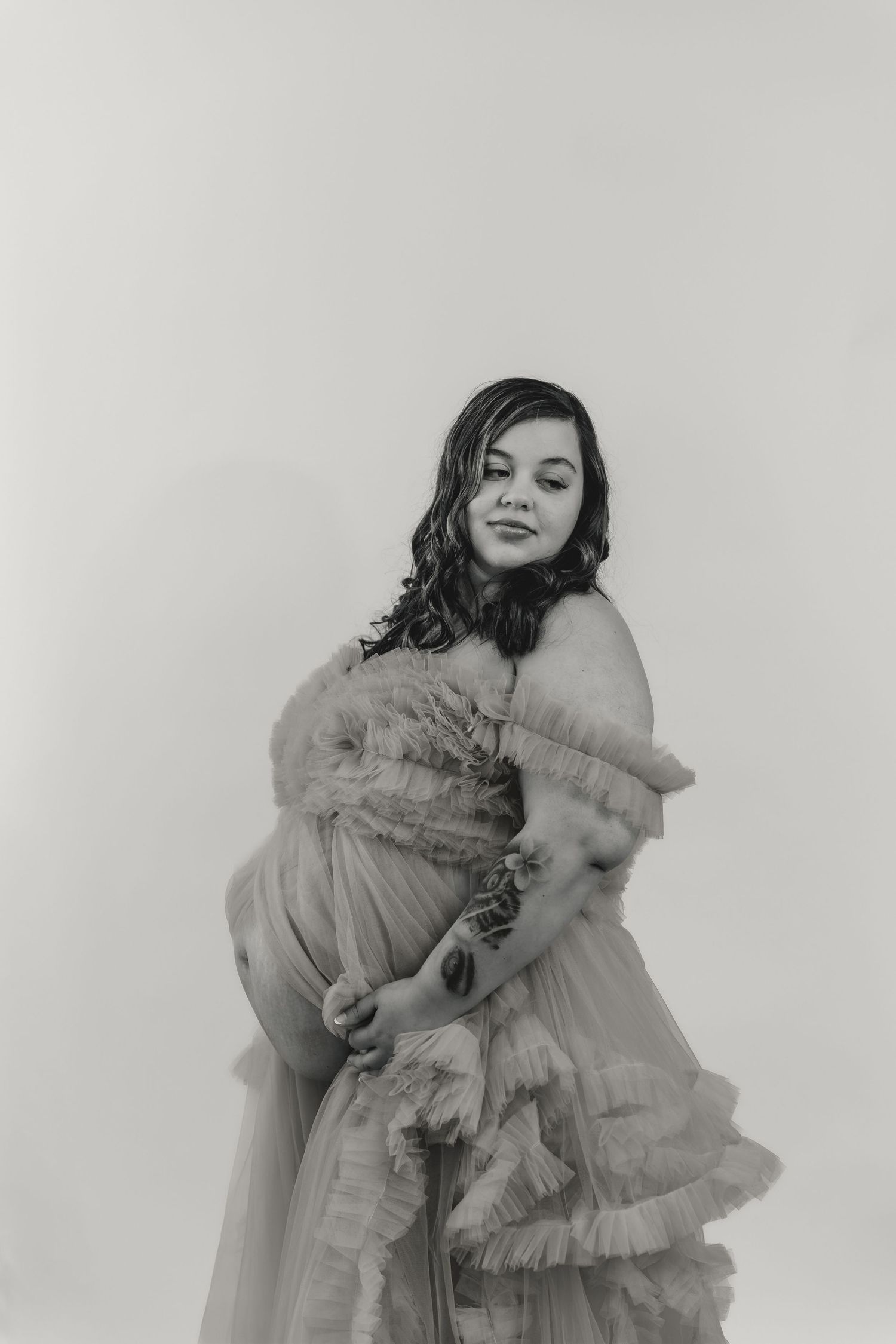 Expecting mother holds her belly in a flowing maternity dress during a maternity session with Central Illinois maternity photographer