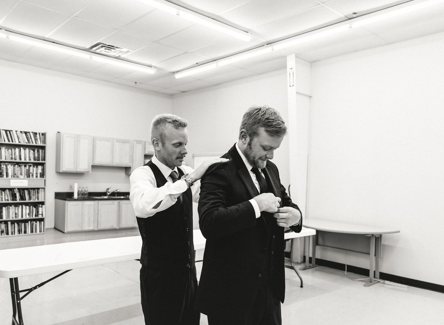 Best man helps groom get ready during getting ready photos with illinois wedding photographer
