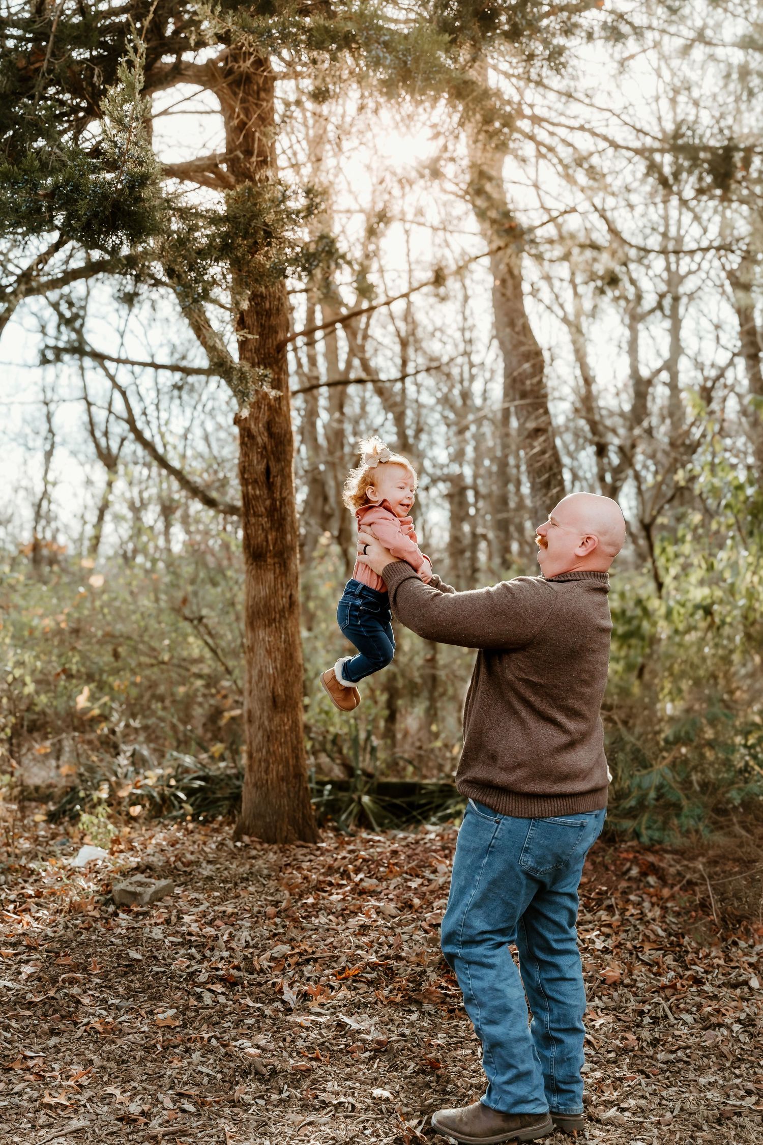 Dad holding his little girl in the air during an extended family photo session