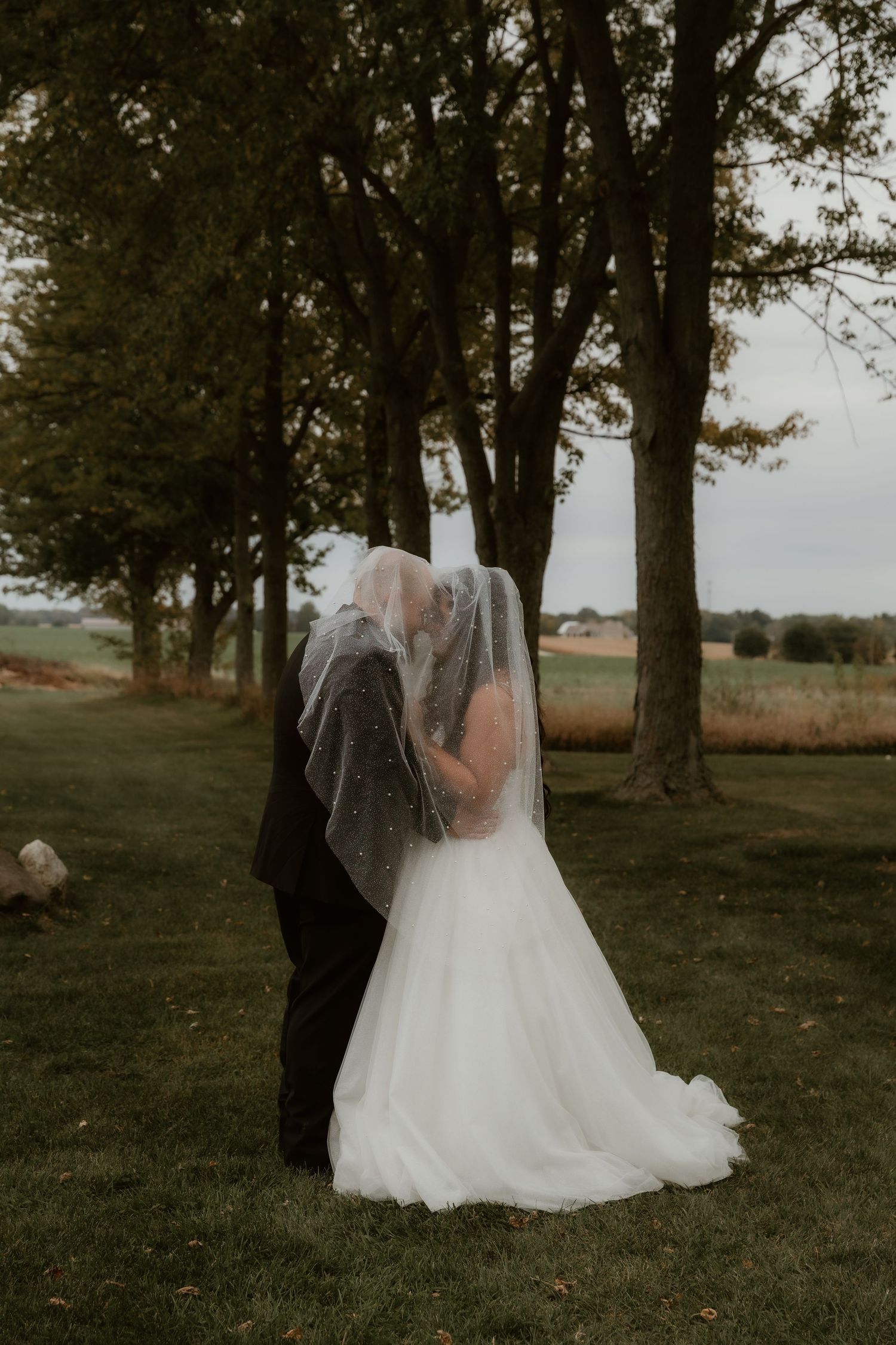 Bride and Groom share a kiss under the veil during wedding portraits at Chapel in the Pines in Sycamore, IL