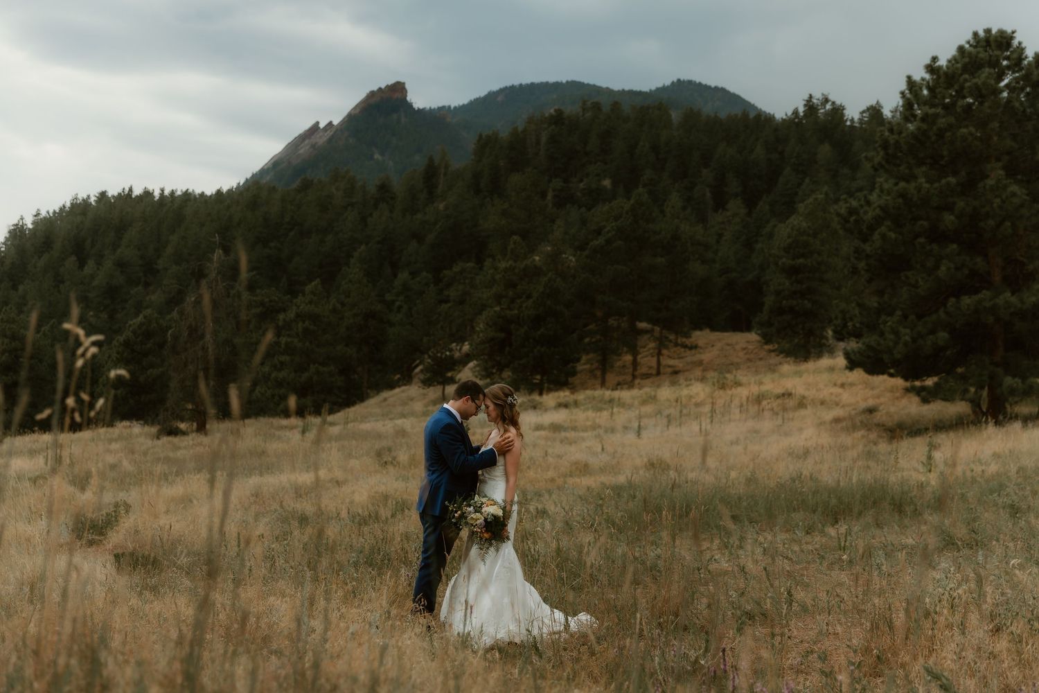 Bride & Groom share an intimate moment in an open field surrounded by mountains during wedding portraits with colorado wedding photographer