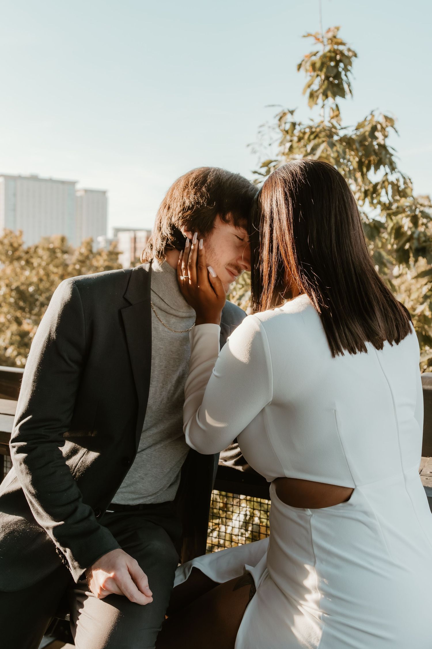 Couple touching heads during an engagement session with sunlight highlighting the engagement ring