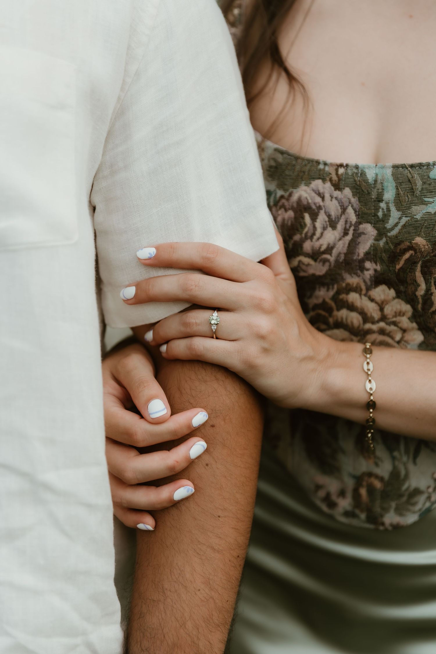 Bride wraps hands around grooms arm and shows off her engagement ring during engagement session with central illinois wedding photographer