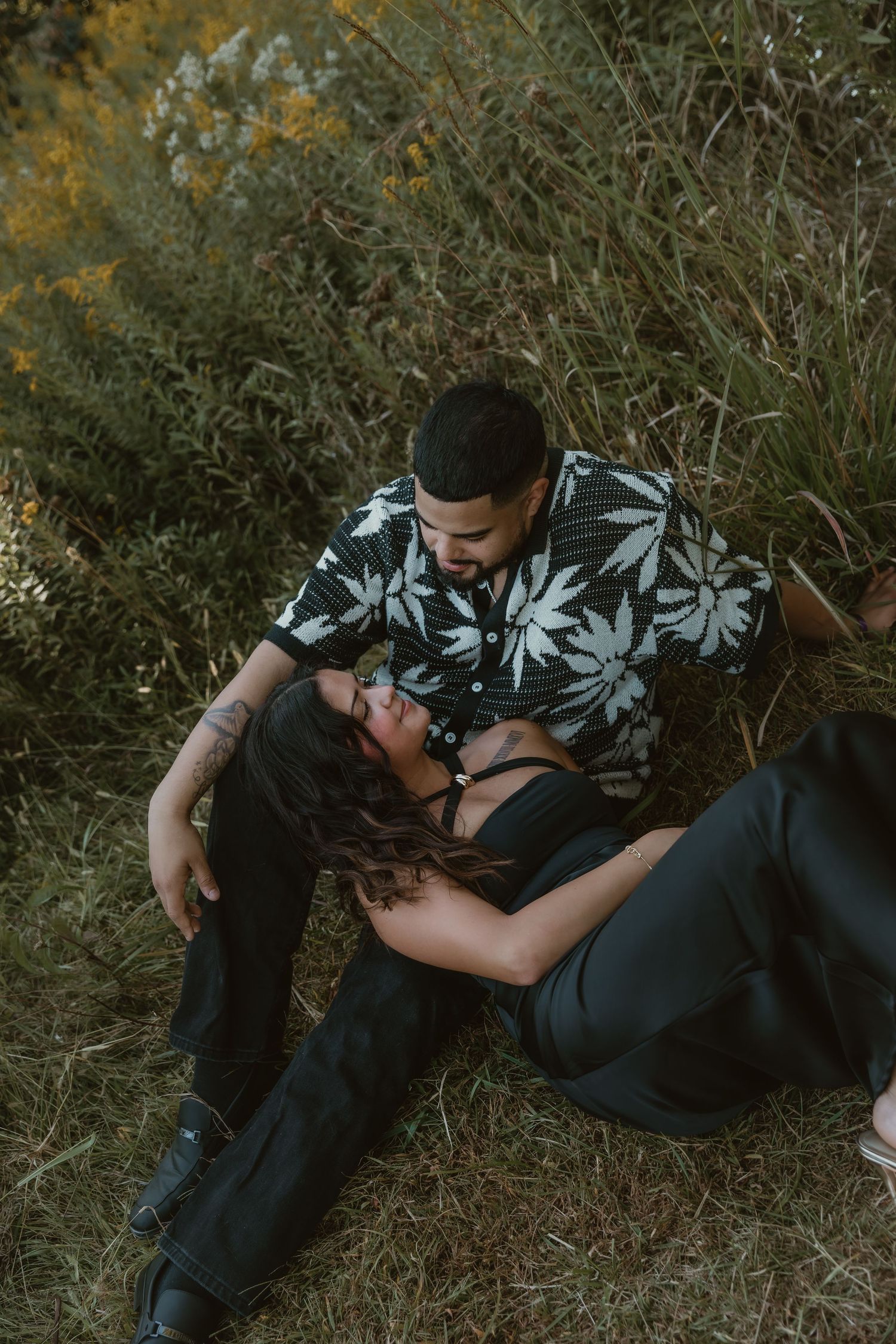 A couple laying in a field of golden rods during their couple session with central illinois couple photographer