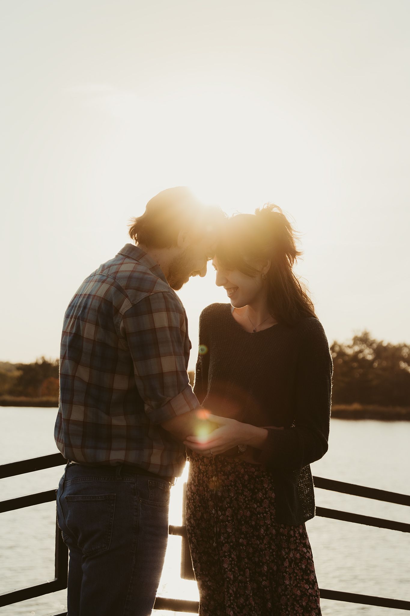 Couple standing on a bridge touching foreheads