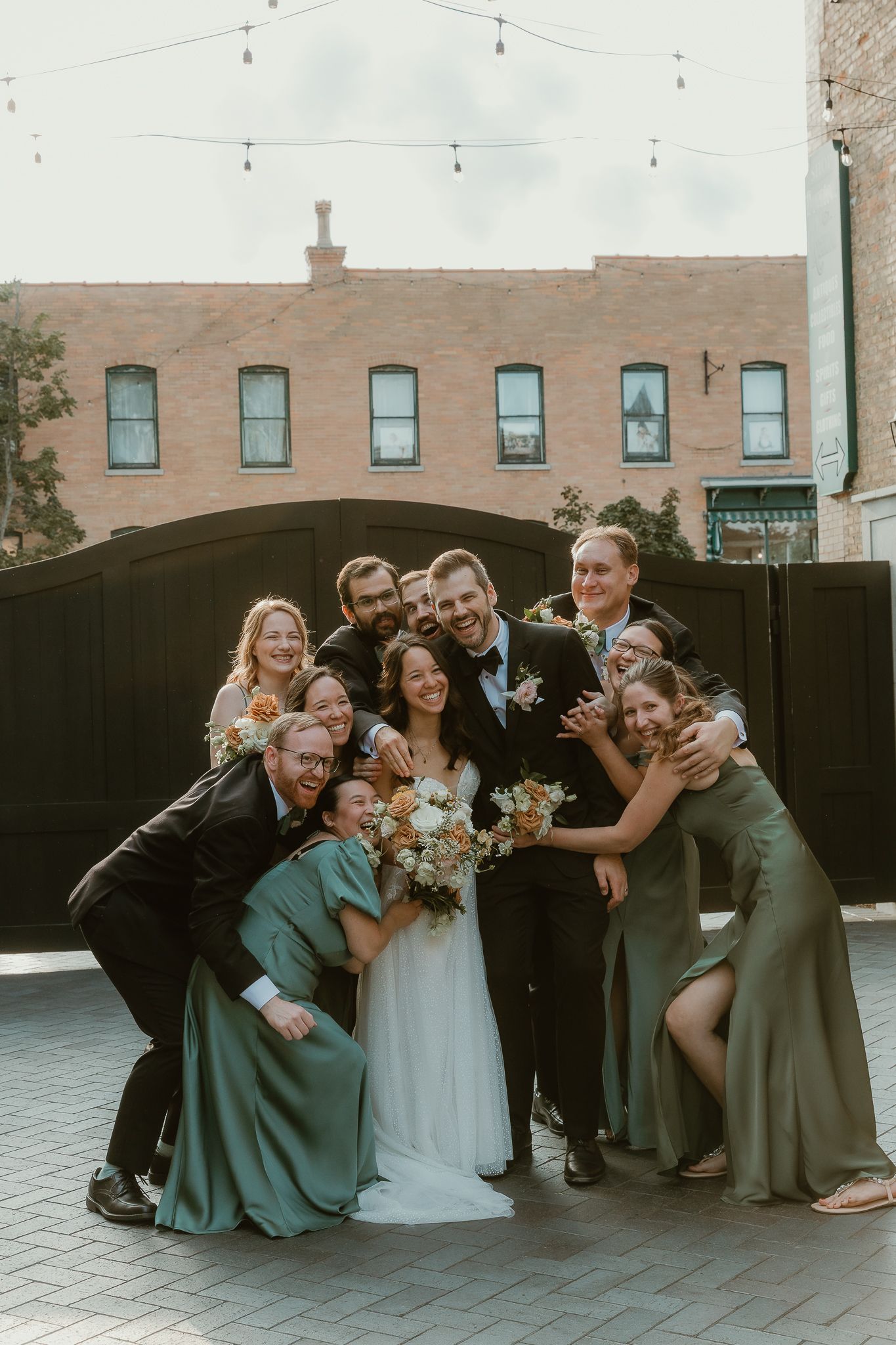 Bride and Groom are squeezed by their wedding party in a big hug during group photos with central illinois wedding photographer