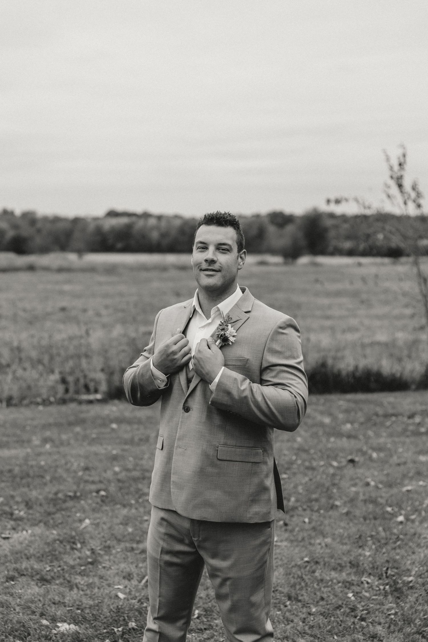Groom poses for his wedding portraits in an open field captured by illinois wedding photographer