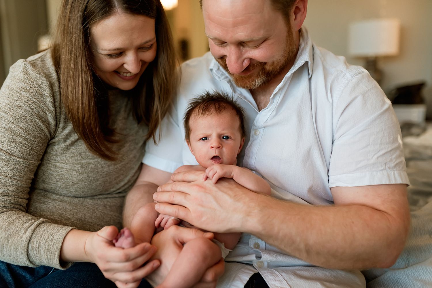 Young family sharing tender moments with their newborn baby at home in a during in home newborn photo session.