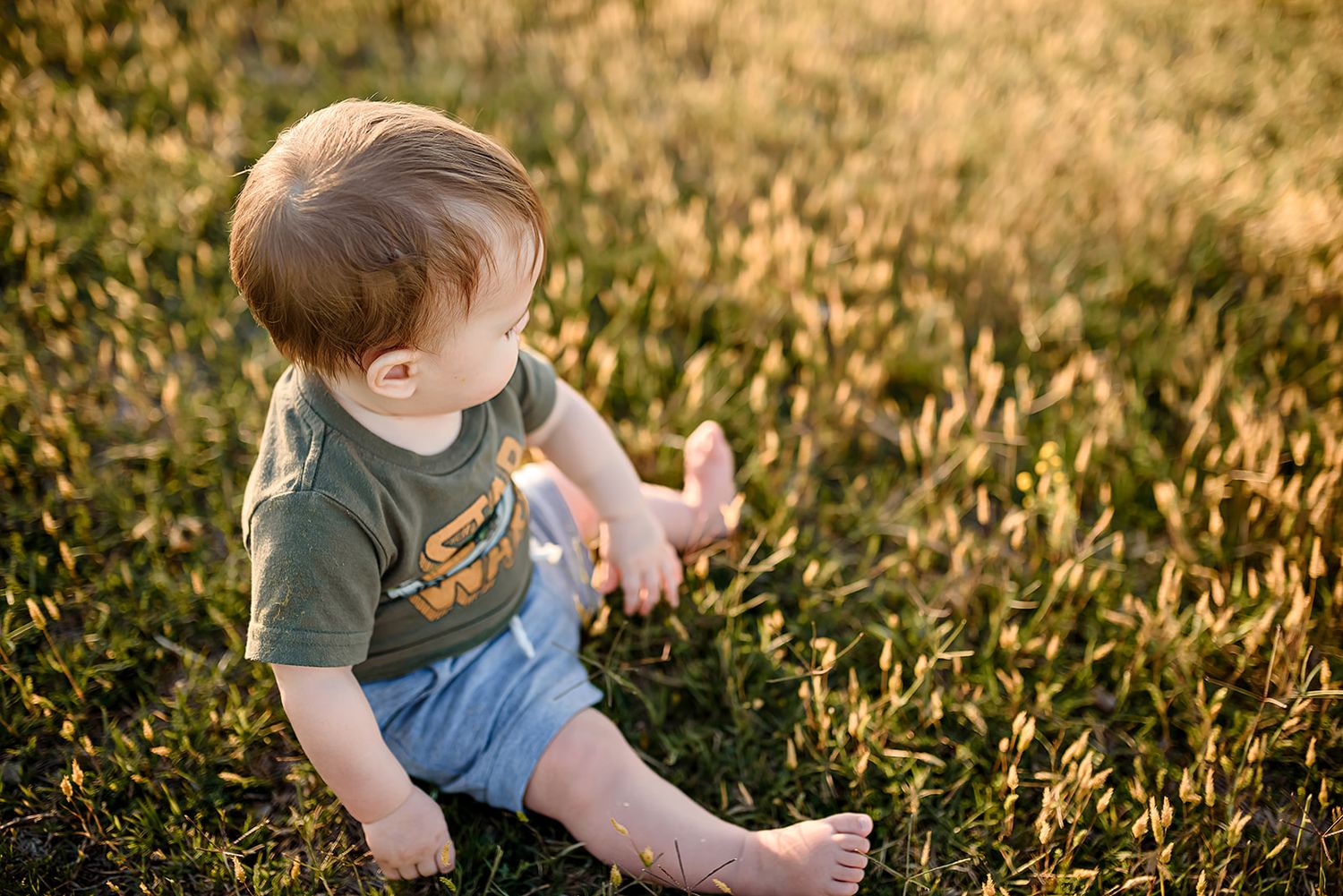 A baby boy sits on golden grass during a warm spring sunset in Scottsdale.