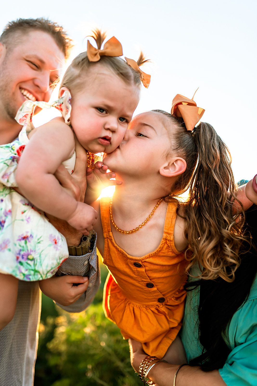 Big sister kisses baby sister’s cheek during golden hour family portraits in Buckeye, Phoenix West Valley.